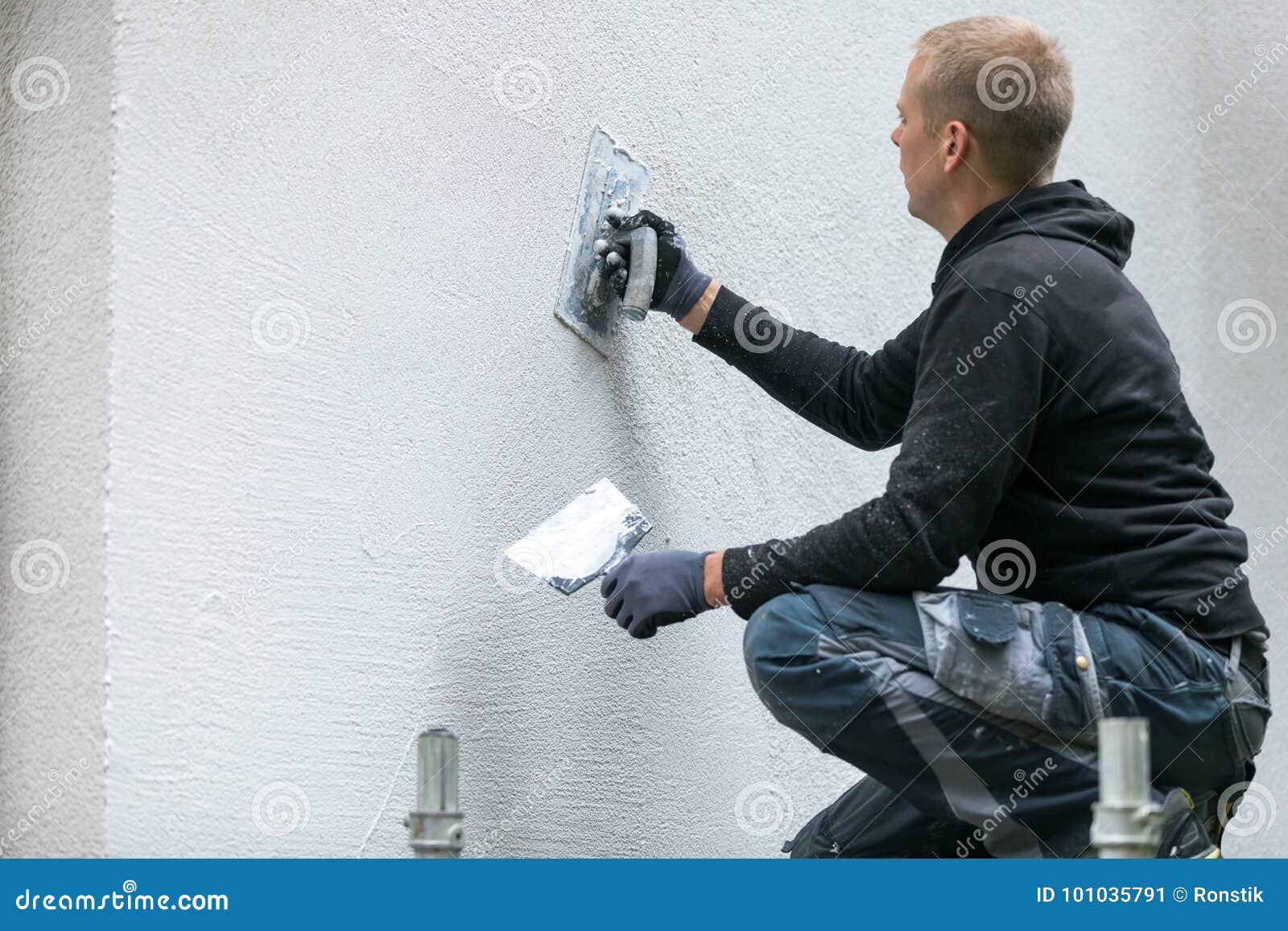 construction worker putting decorative plaster on house exterior