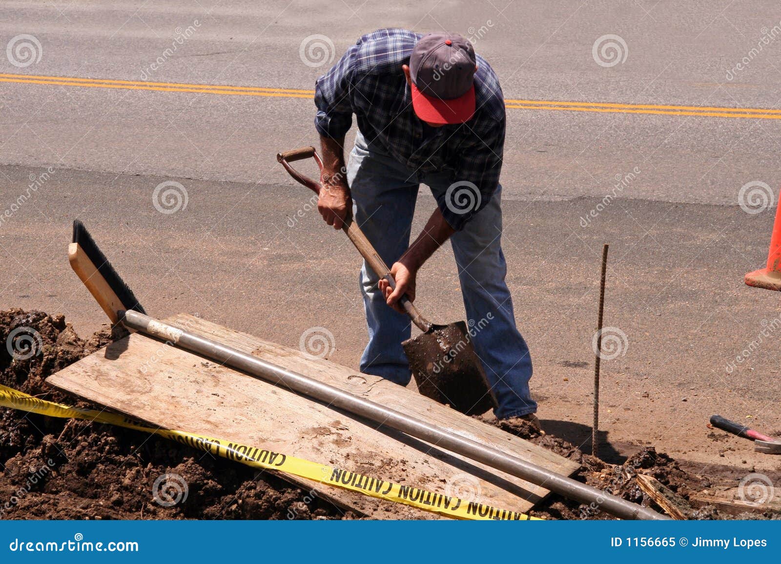 Worker With Shovel Is Digging A Pit On Construction Site. Concept Of