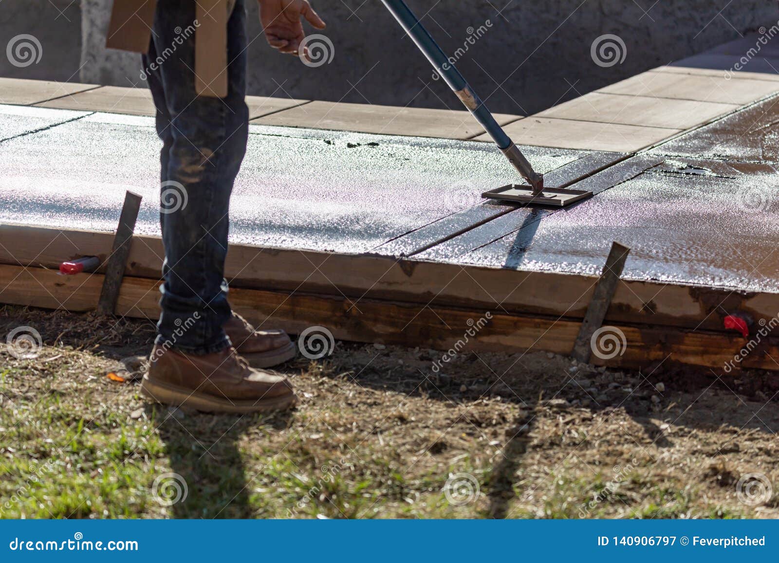 Construction Worker Smoothing Wet Cement with Long Handled Edger Tool