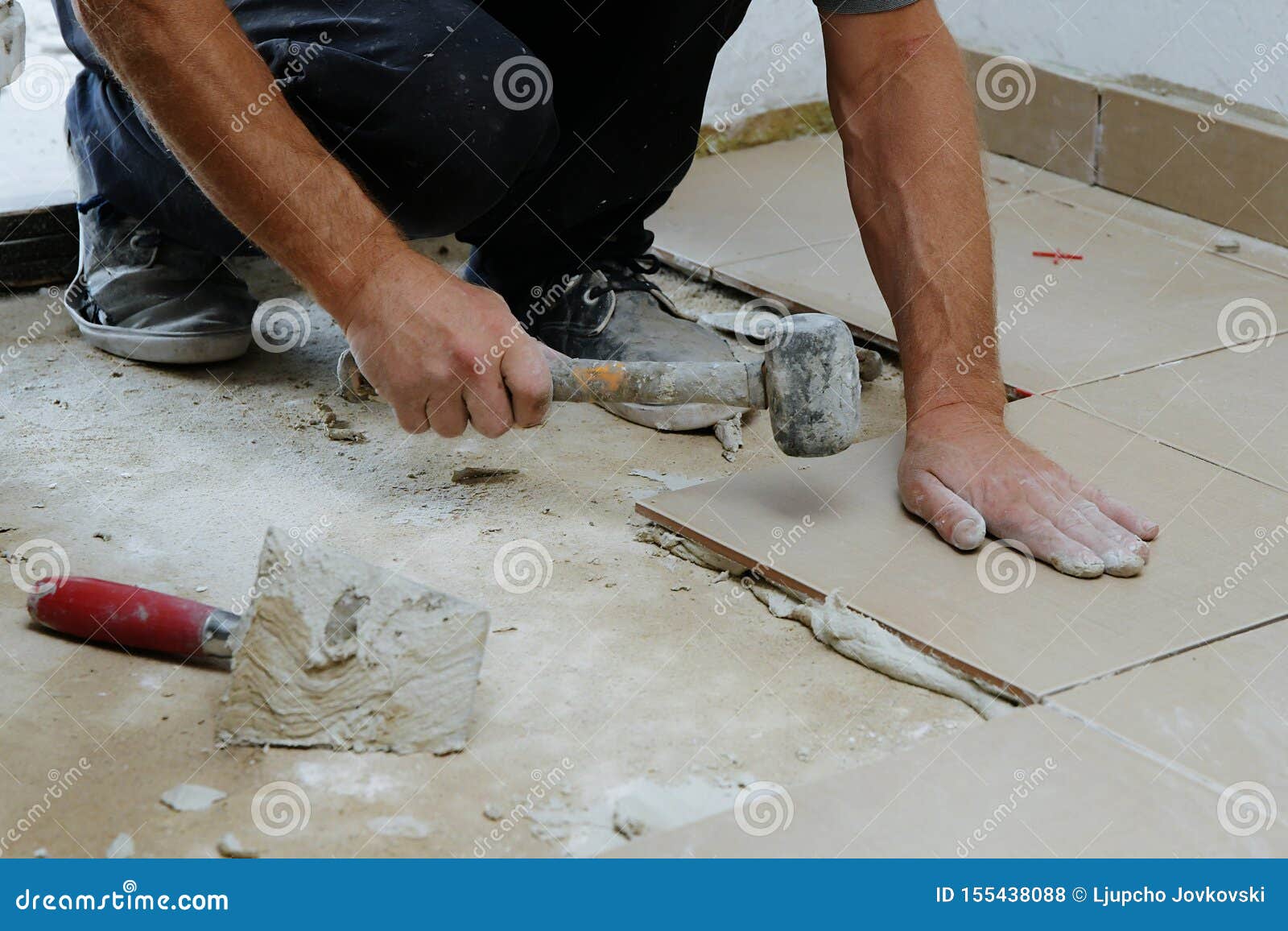 Construction Worker Is Tiling Floor At Home Laying Tiles On The