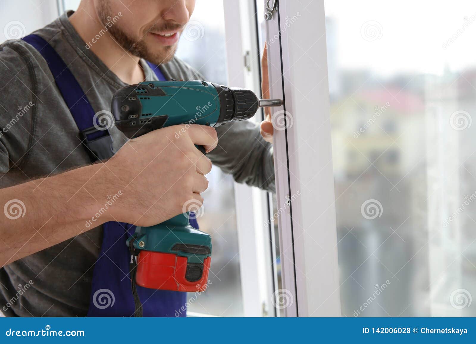 Construction Worker Using Drill while Installing Window Indoors Stock