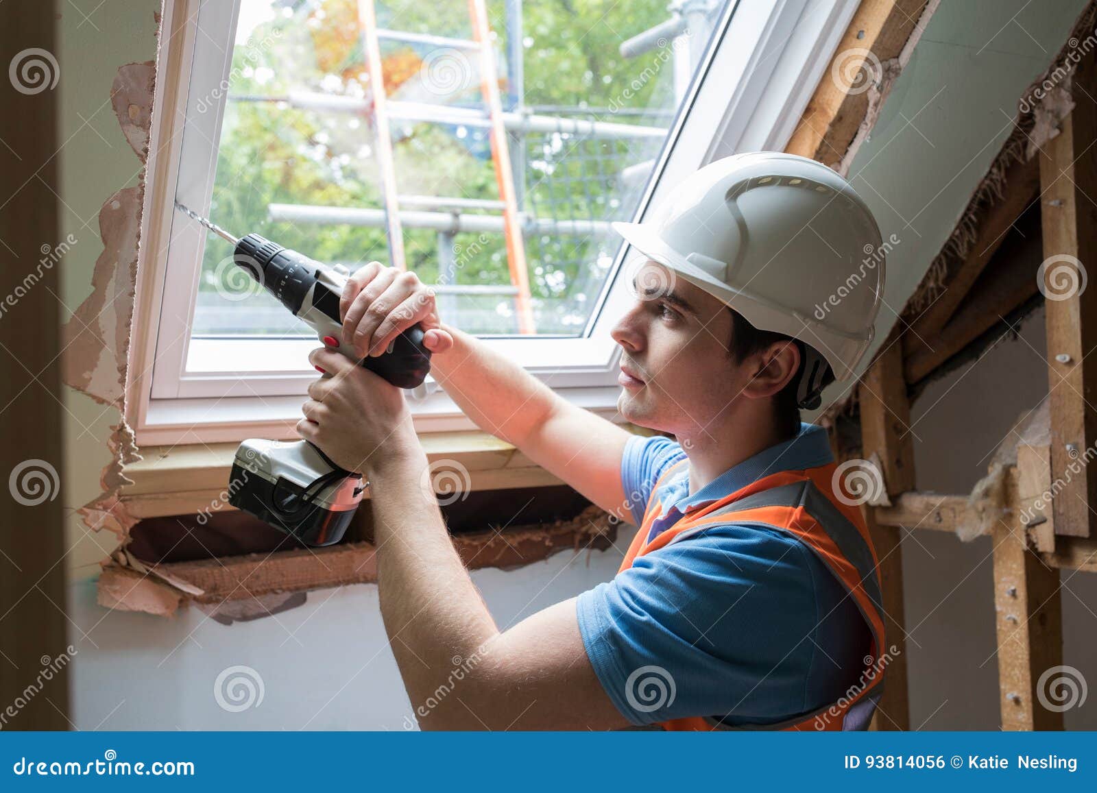 Construction Worker Using Drill To Install Replacement Window Stock