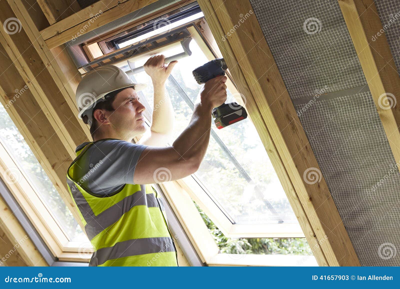 construction worker using drill to install window