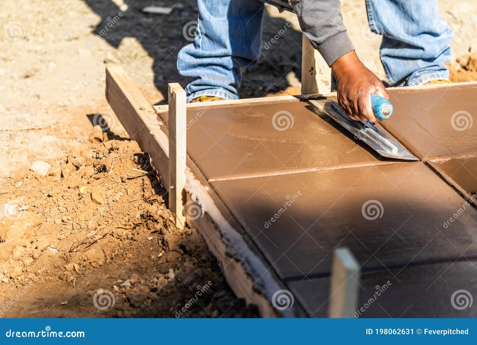 construction worker using trowel on wet cement forming coping around new pool