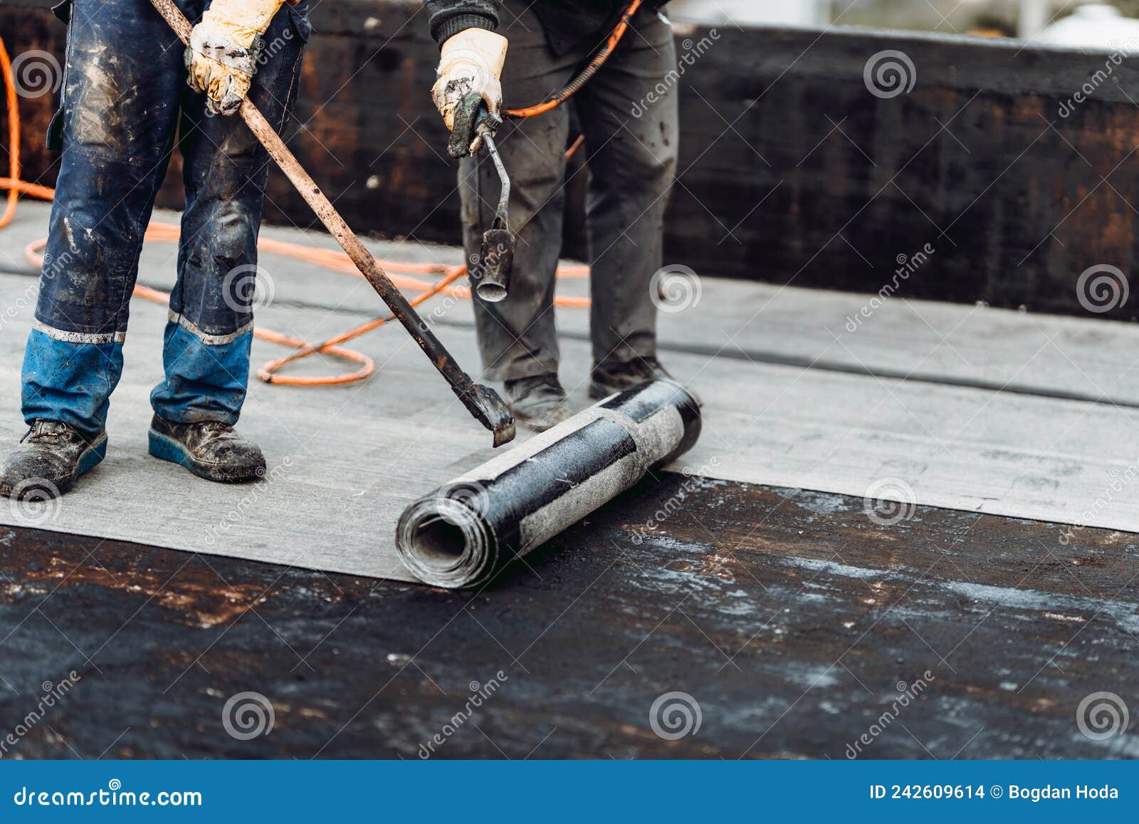 roofers installing rolls of bituminous waterproofing membrane
