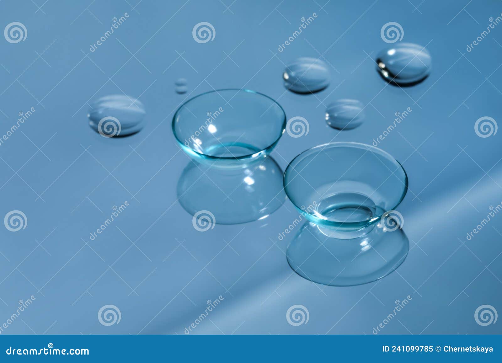 Contact Lenses and Drops of Water on Light Blue Reflective Surface
