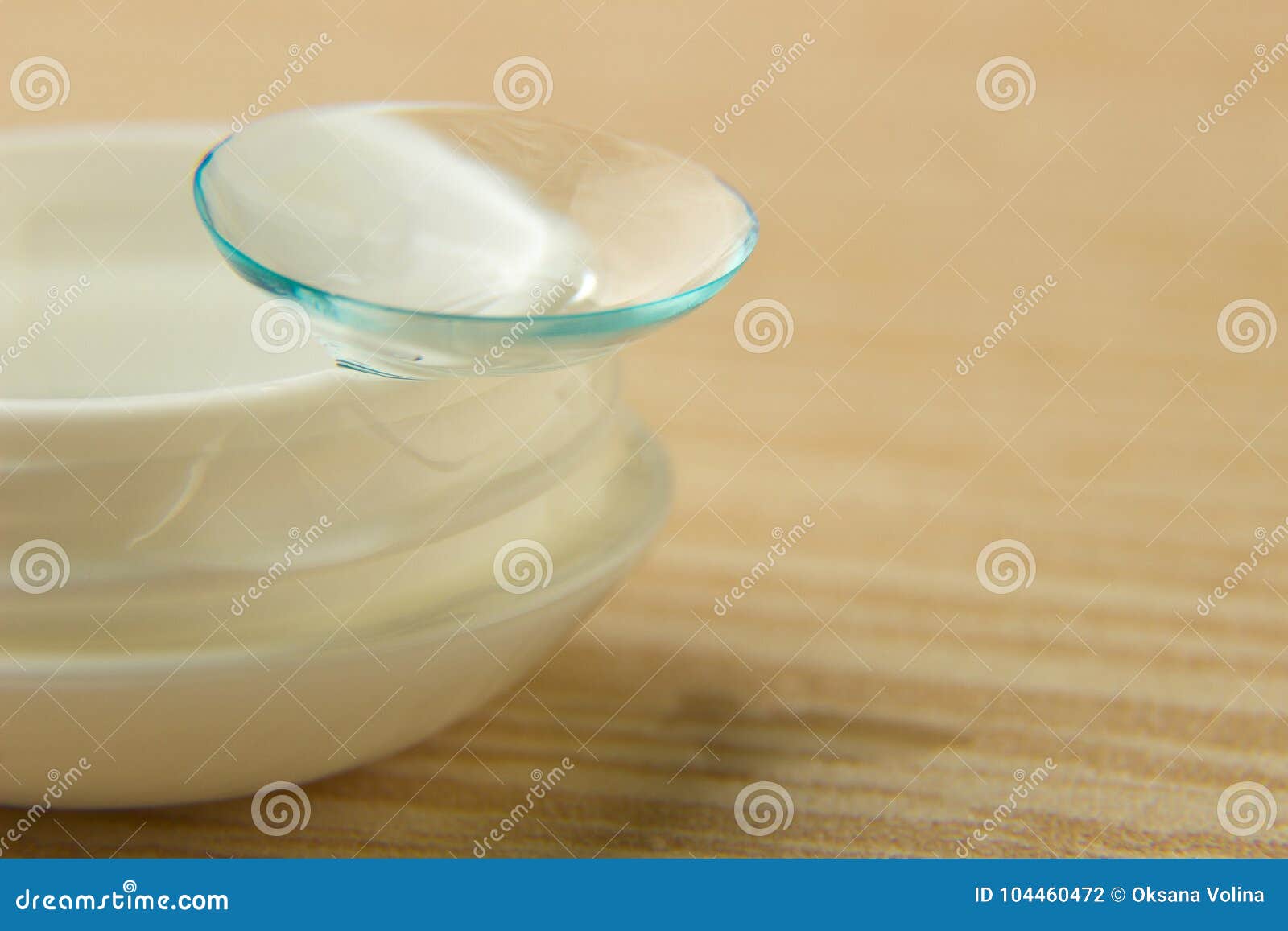 contact lenses for the eyes and a white container with a solution on a wooden table