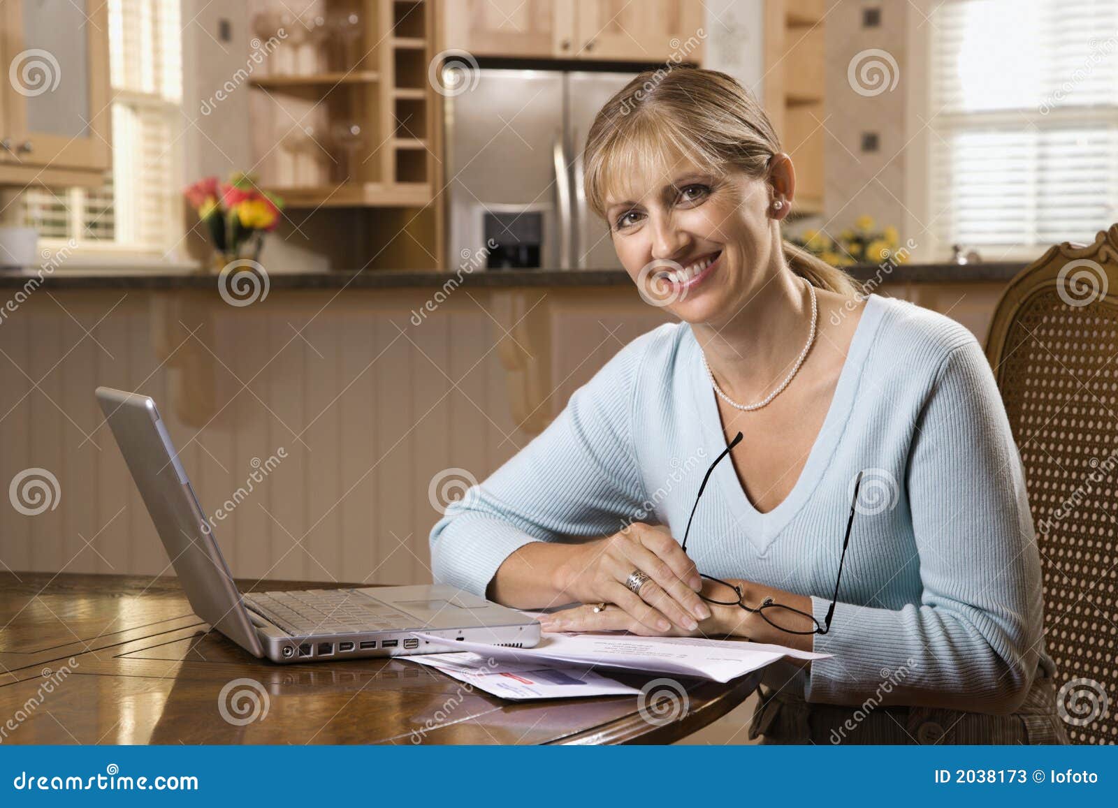 Contas pagando da mulher no computador. Contas pagando da mulher caucasiano do meados de-adulto no computador portátil que olha o visor e o sorriso.