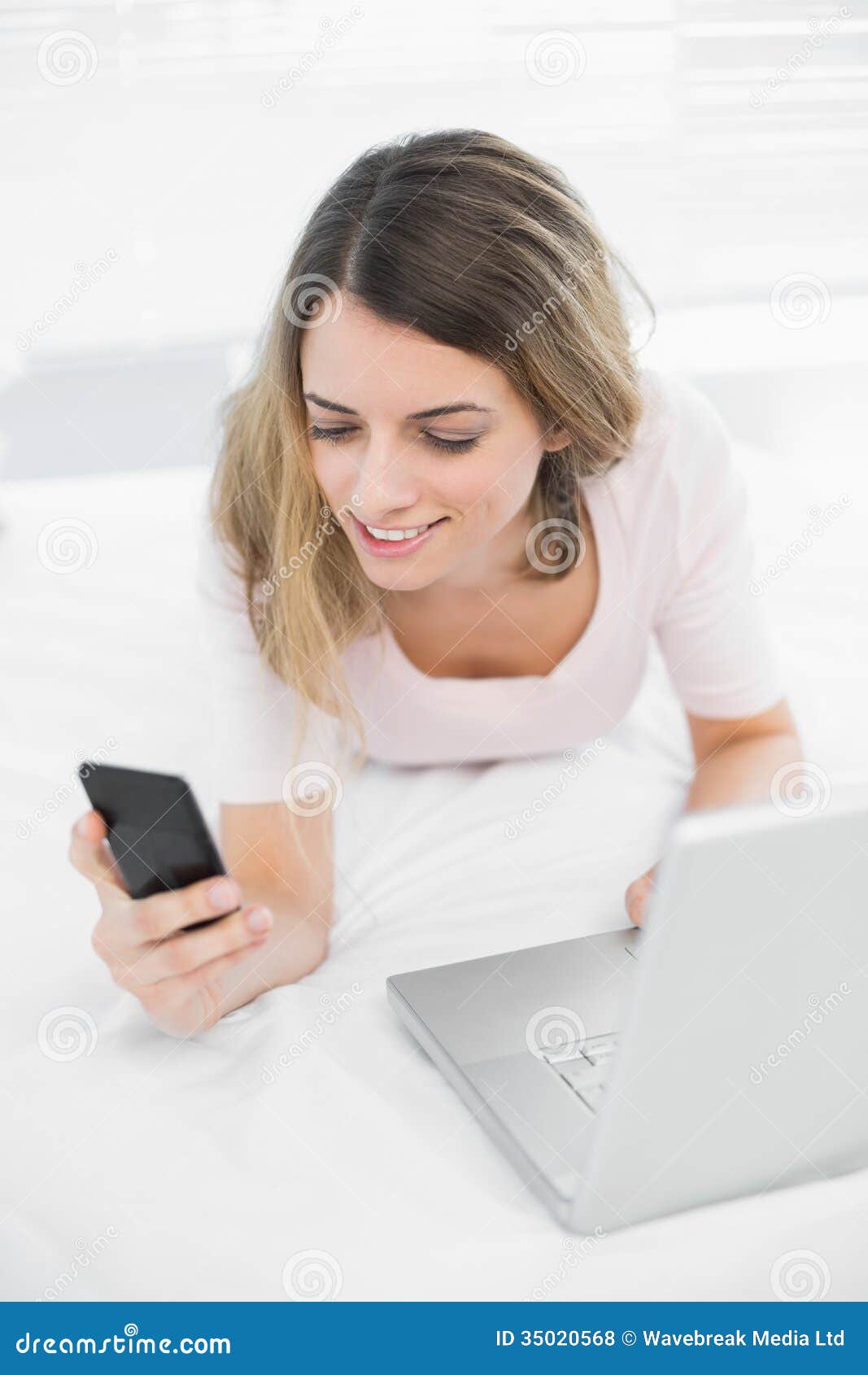 Content Young Woman Using Her Smartphone Lying on Her Bed Stock Photo ...