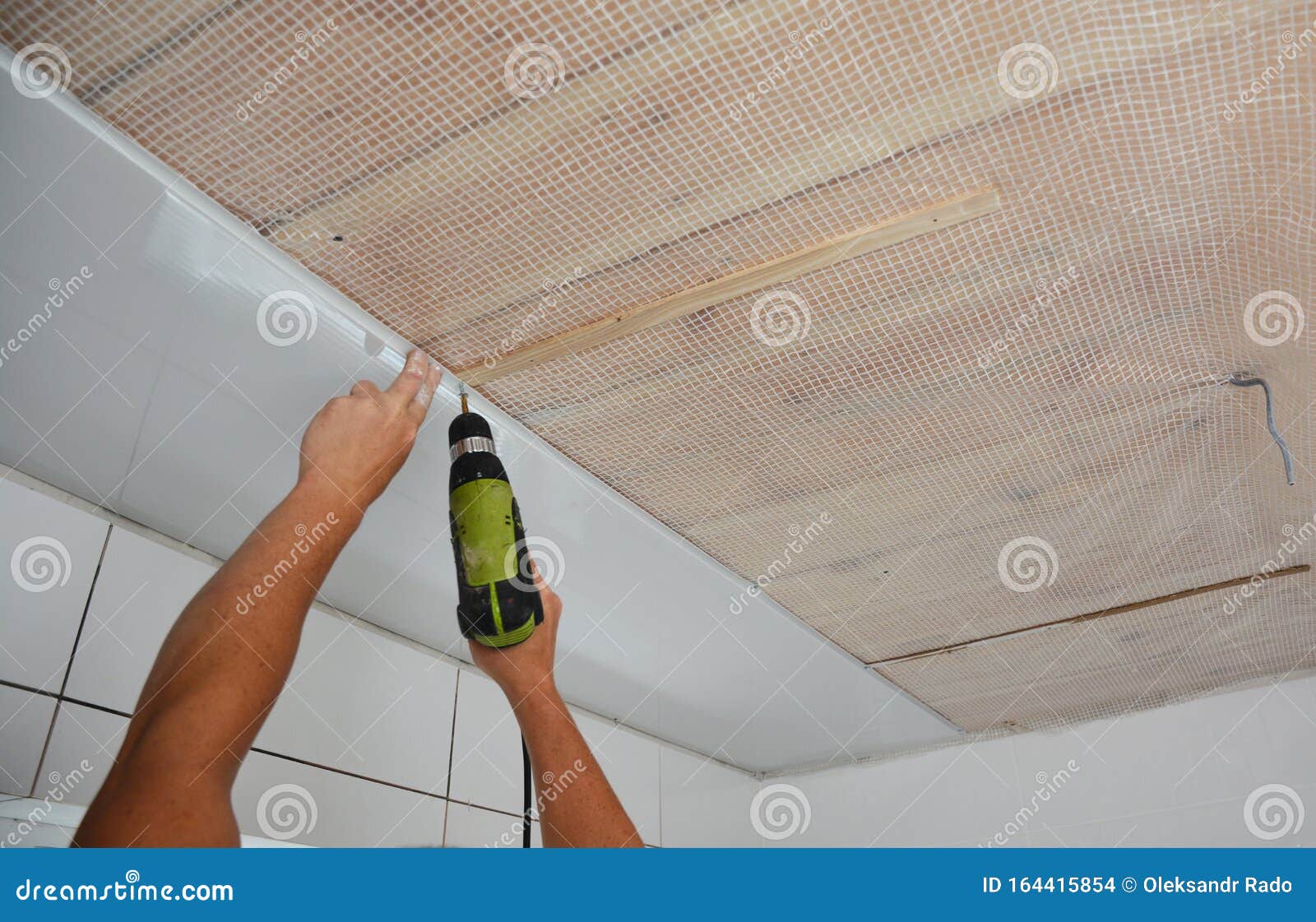 Contractor Installing White Pvc Ceiling Boards With Gun In The