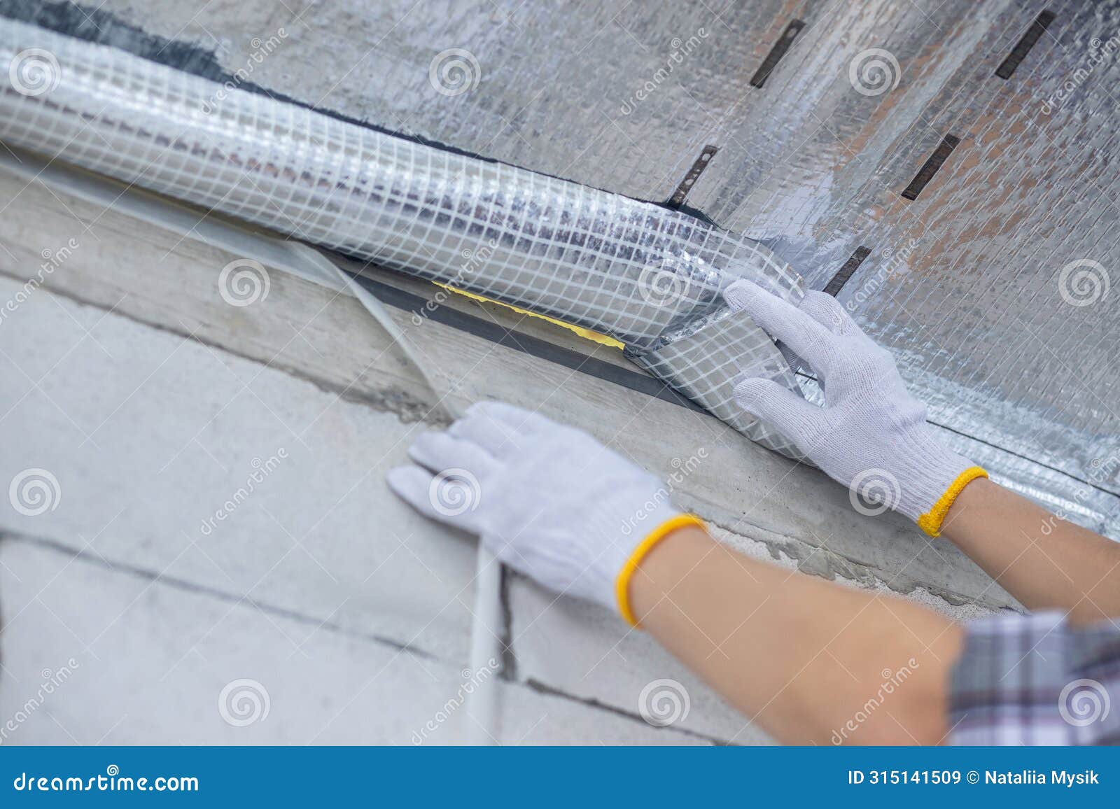 a contractor tapes a vapor barrier between a house and a cold attic