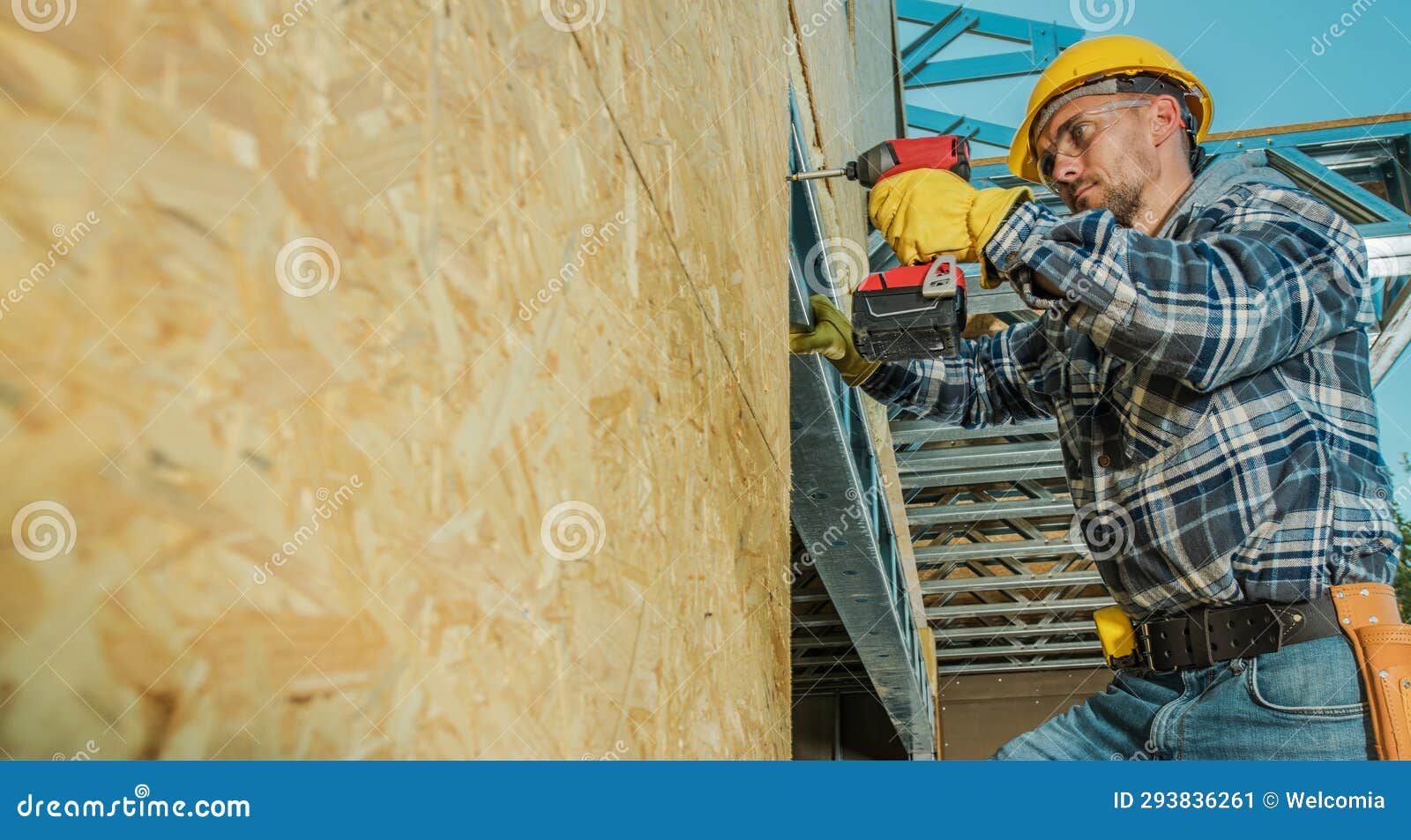 Contractor Worker Installing Plywood Board Using Drill Driver Stock