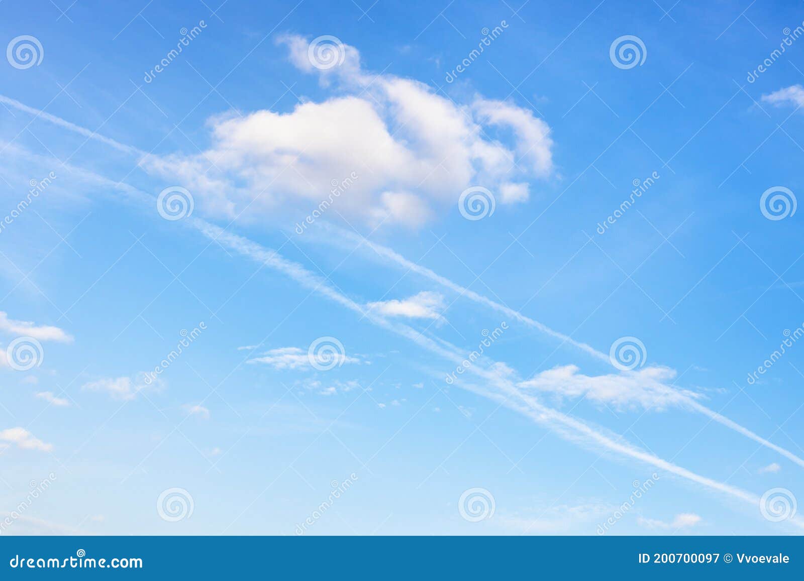 contrail and fluffy cumuli clouds in blue sky