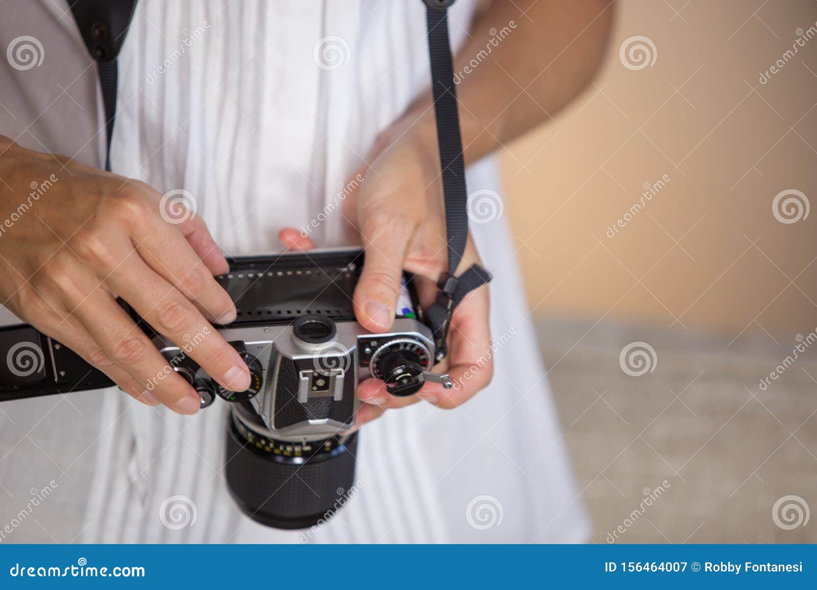 contrast between old and modern times: a young woman with a vintage camera around her neck fiddles with her smartphone