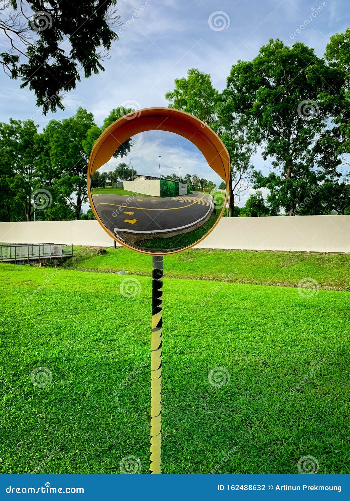 Convex Safety Mirror Mounted on Traffic Pole at Road Curve. Asphalt