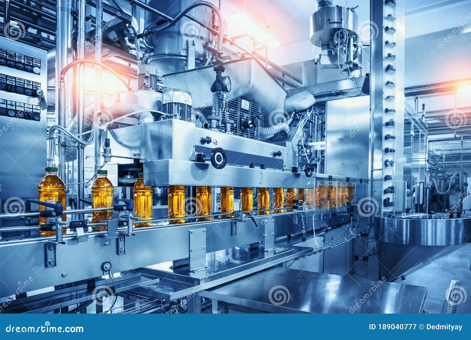 conveyor belt with juice bottles on beverage factory interior in blue color