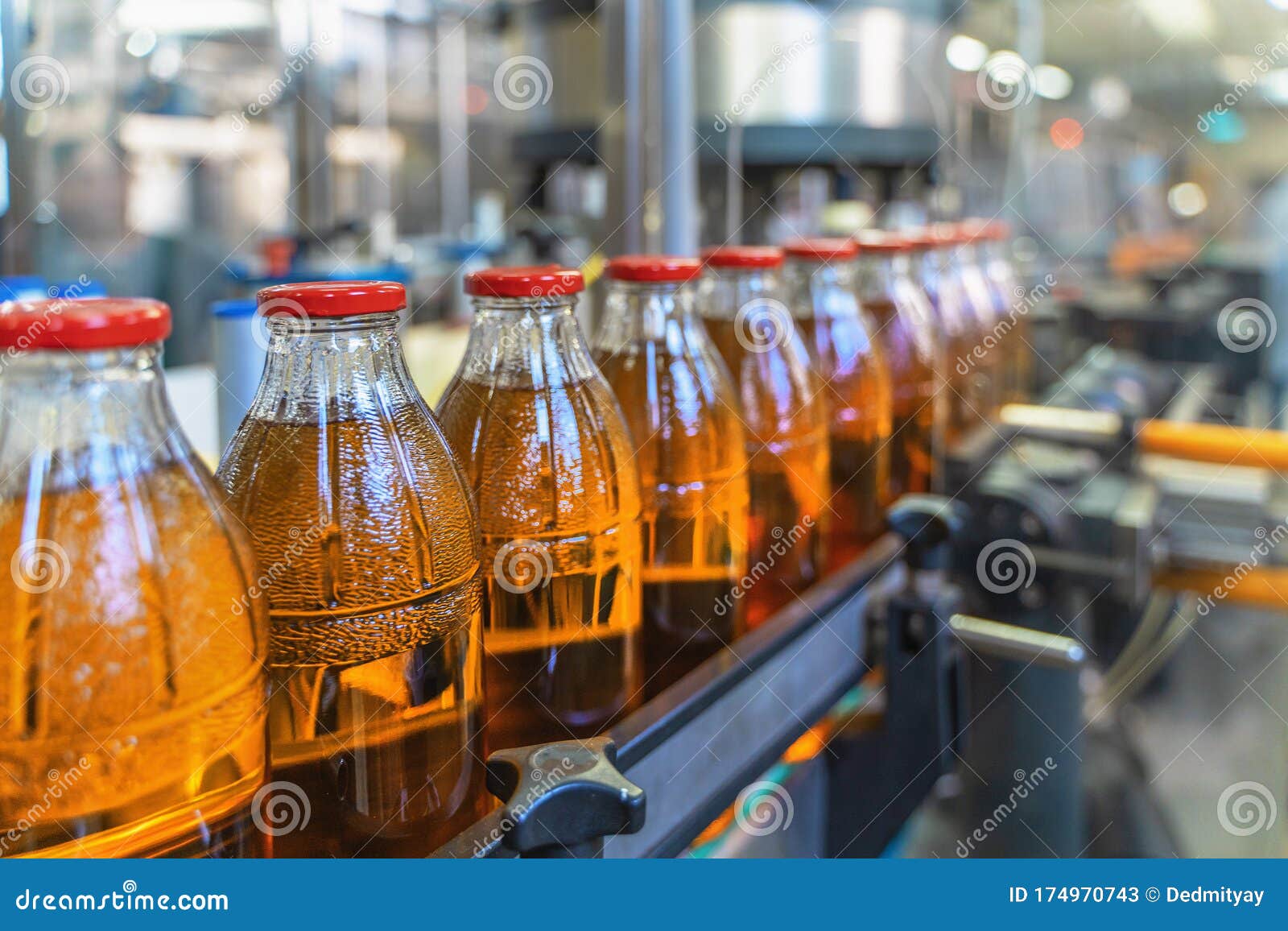 conveyor belt, juice in bottles on beverage plant or factory interior, industrial production line, selective focus