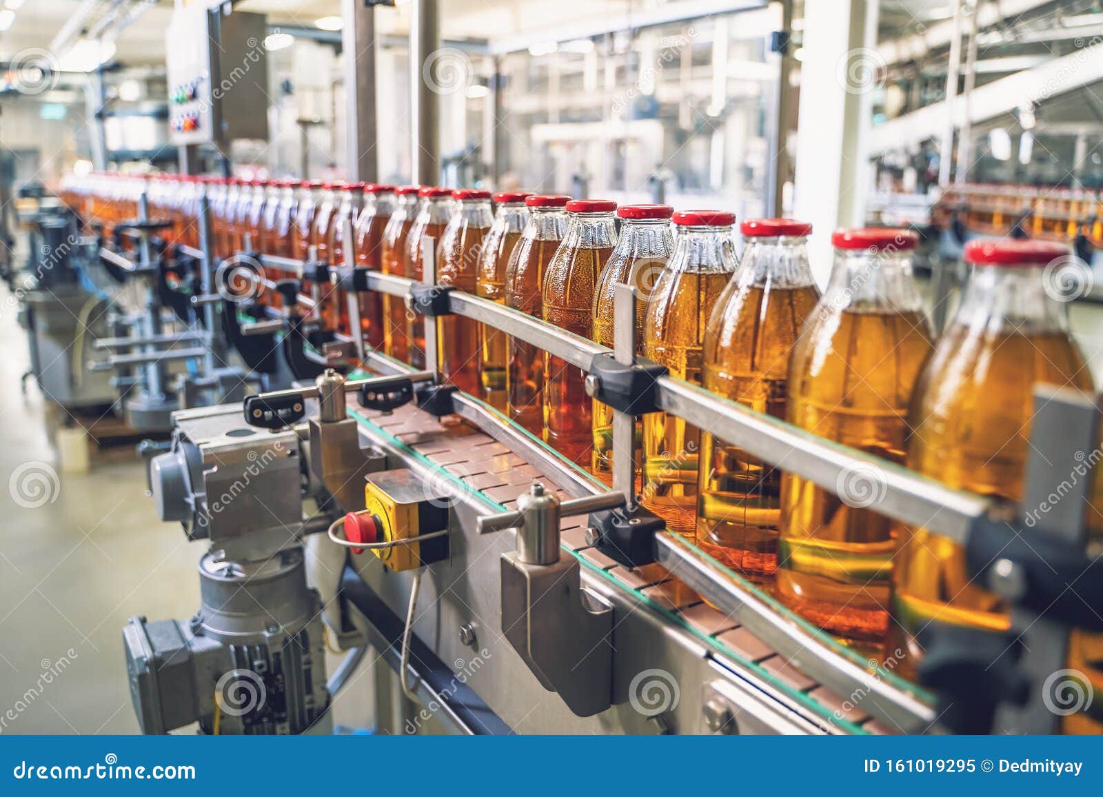conveyor belt, juice in glass bottles on beverage plant or factory interior, industrial manufacturing production line