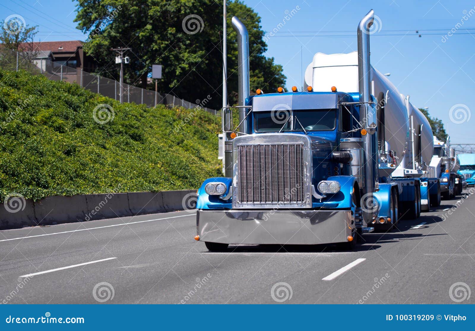 convoy of big rigs semi trucks on the road with blue classic american bonnet semi tractor with bulk trailer