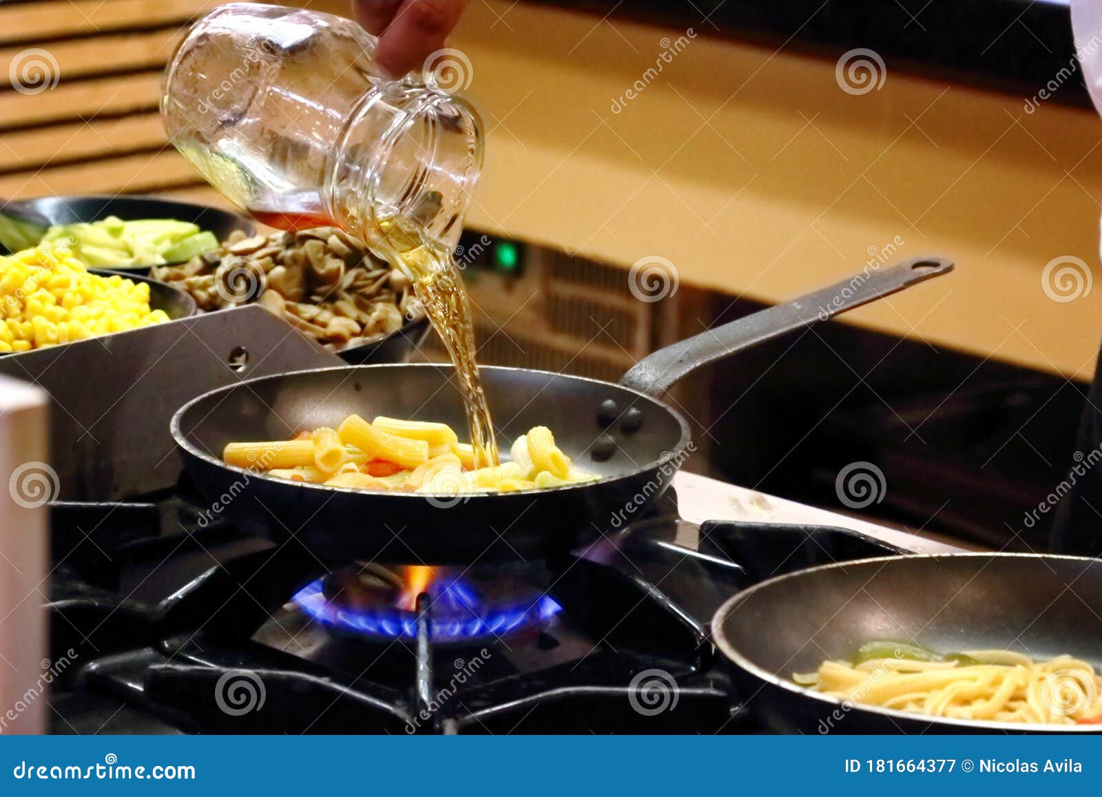 cook pouring sauce from a jug into a bowl with pasta