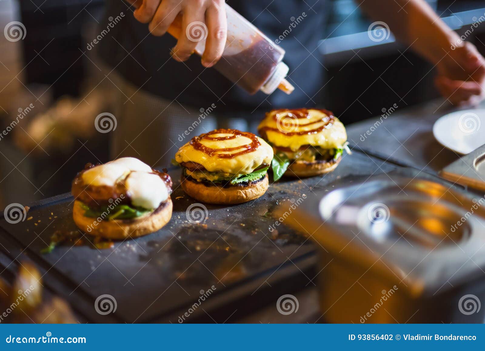Cook Preparing Burger Adding the Sauce on the Cream Cheese. Stock Photo