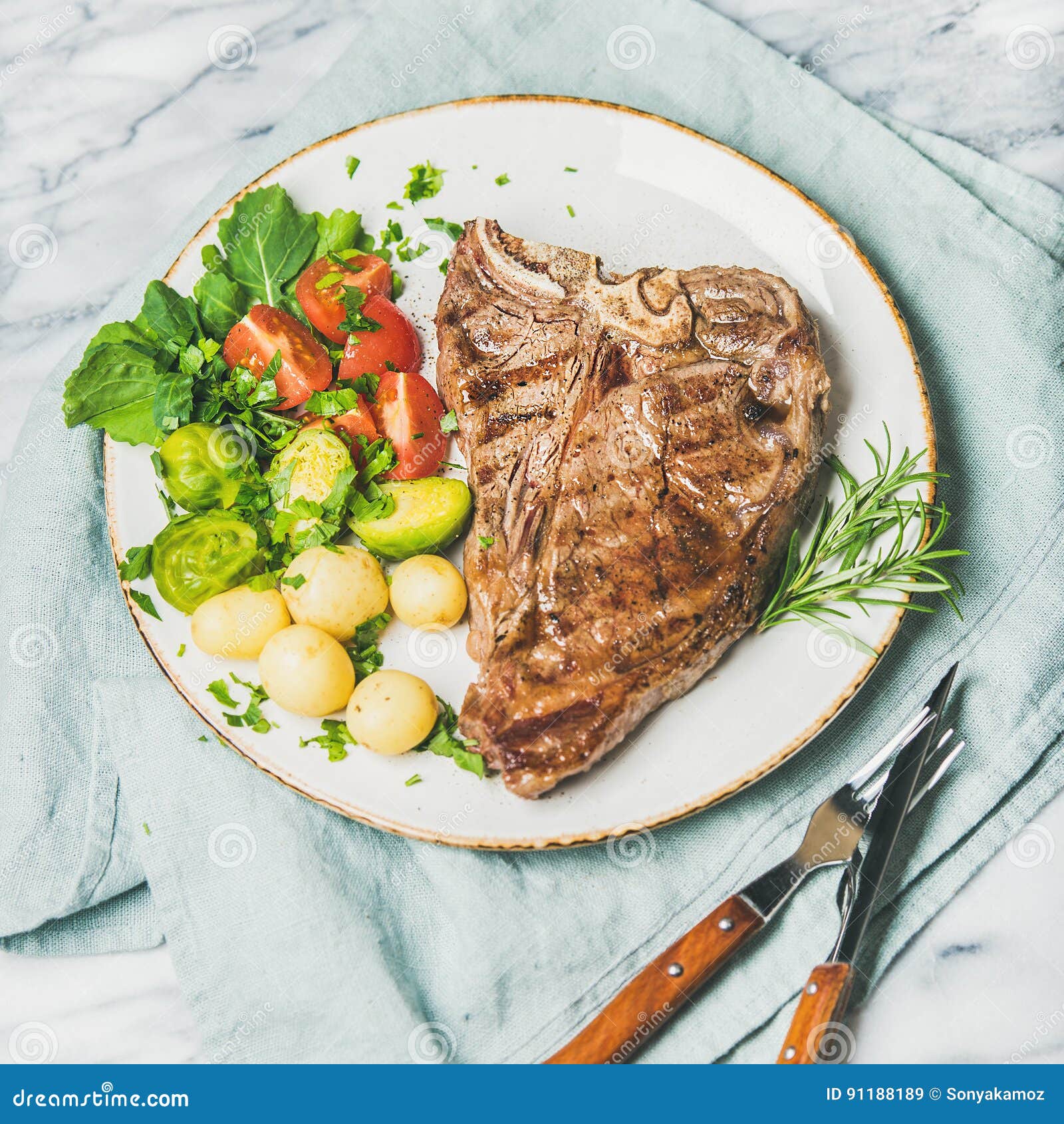 cooked beef tbone steak with vegetables and rosemary, square crop