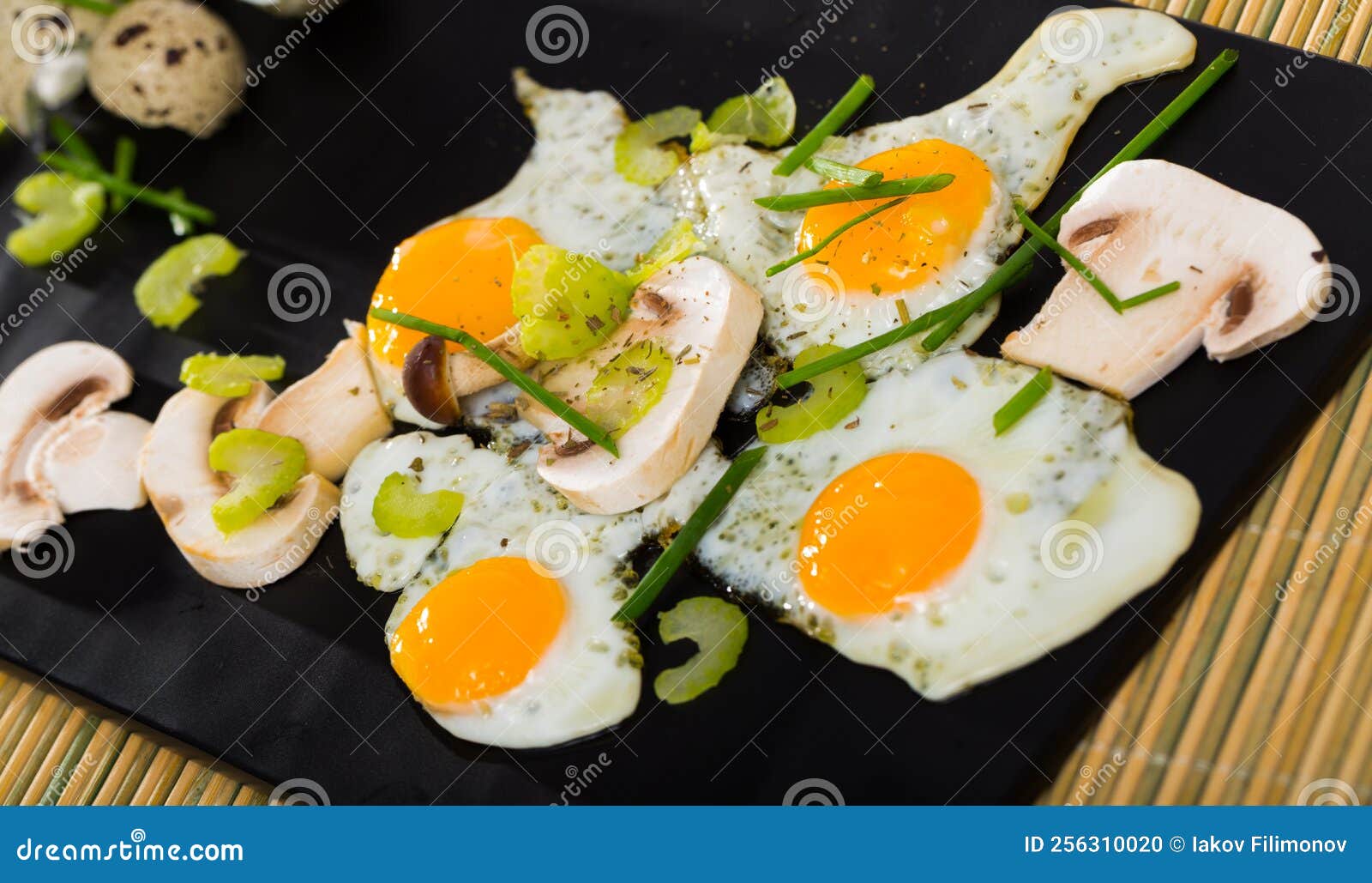 Cooked Fried Quail Eggs and Champignons Mushrooms at Plate on Table