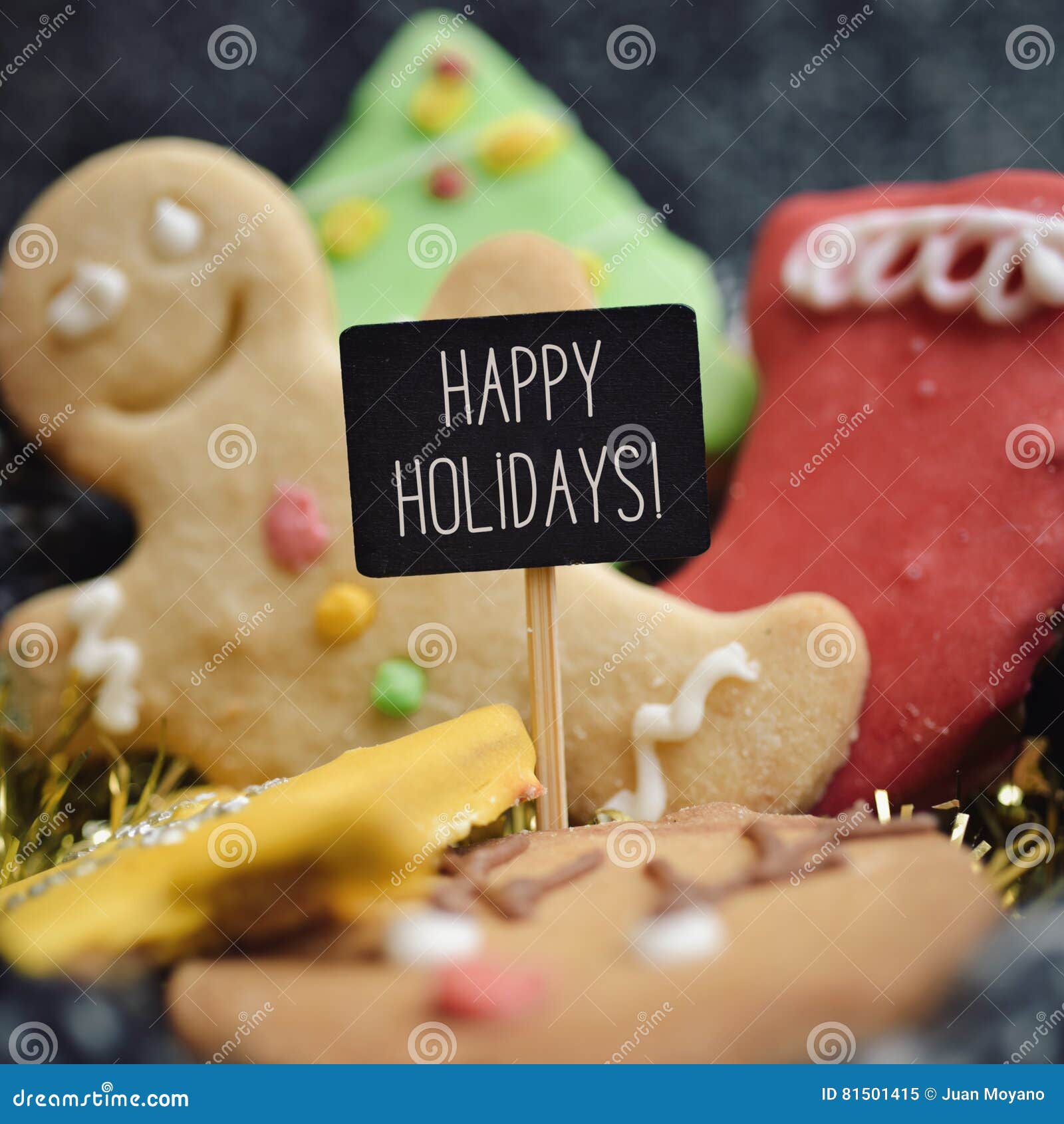 Cookies e texto do Natal boas festas. Close up de uma pilha de cookies do Natal com formas e cores diferentes e um quadro indicador preto com o texto boas festas escrito nele