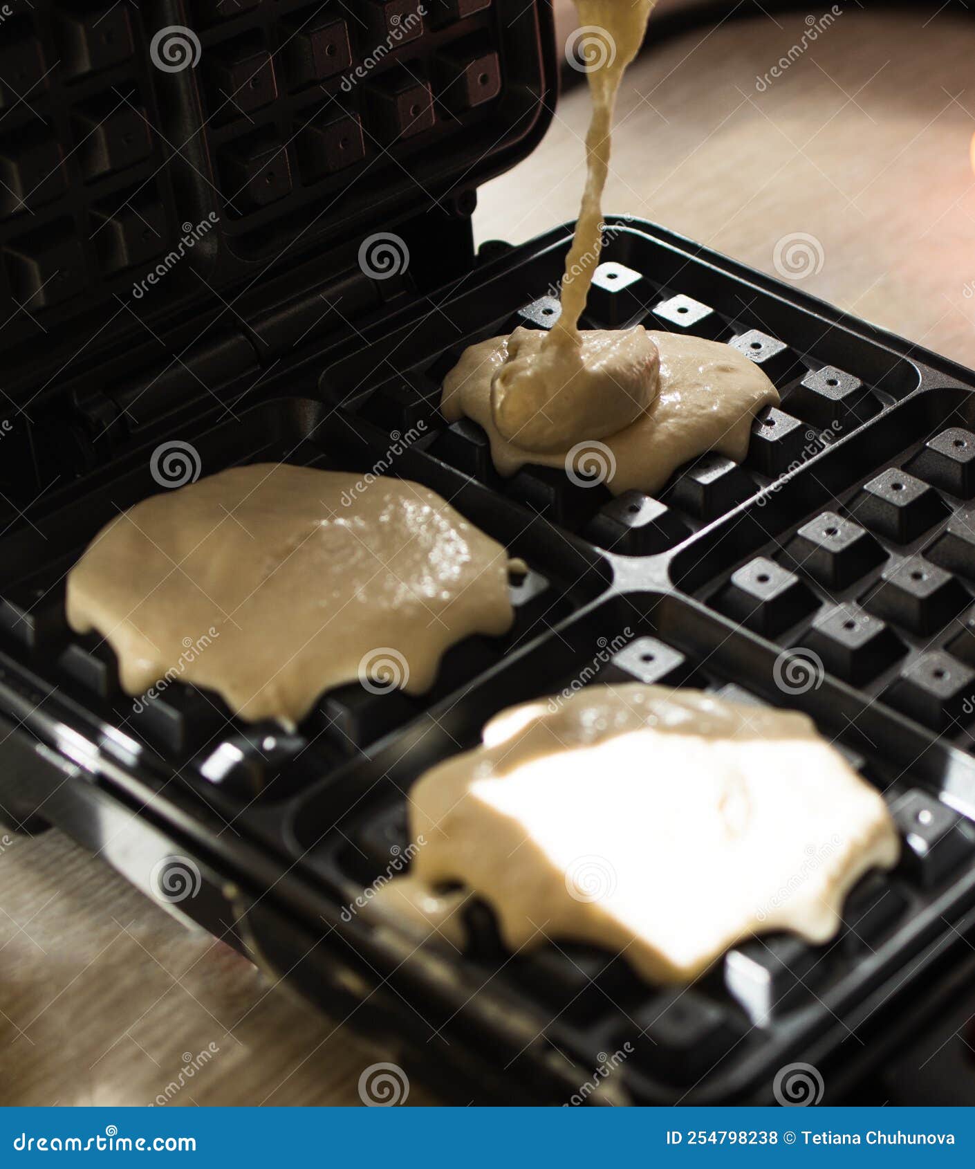 Cooking Belgian Waffles in a Waffle Iron. Pour in the Dough Stock Photo
