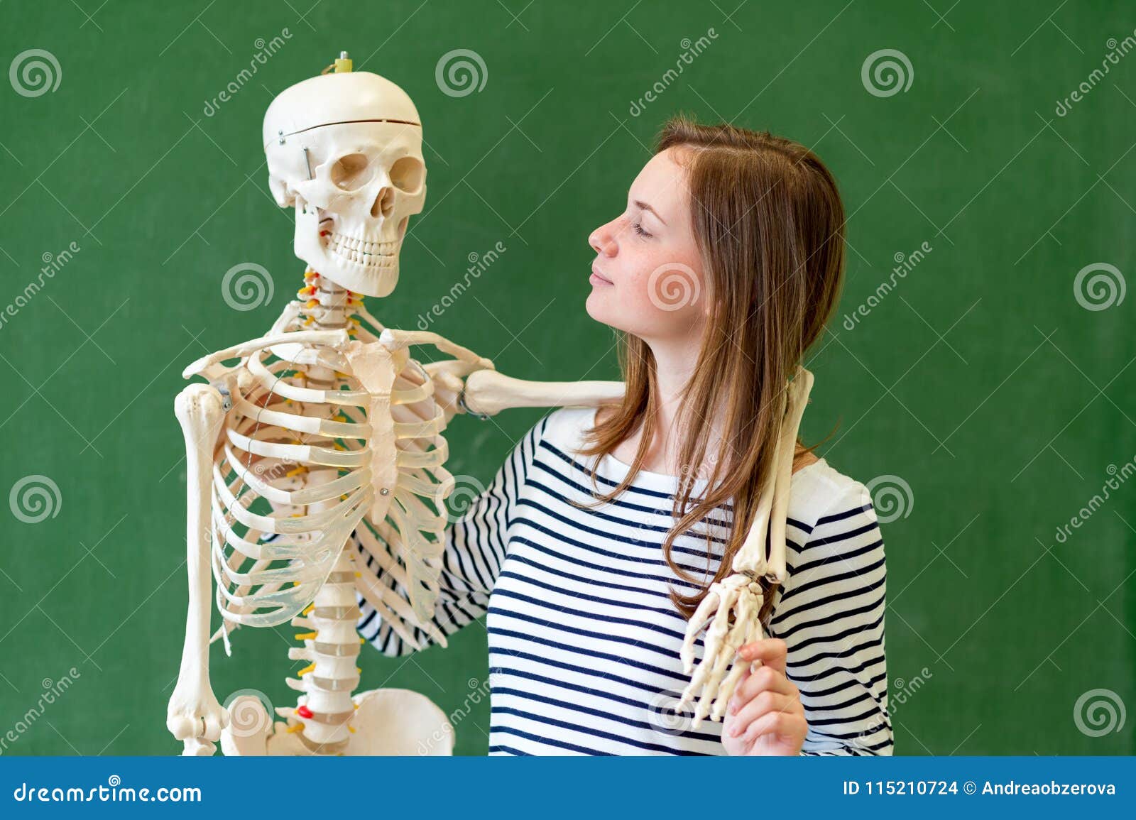 cool female high school student portrait with an artificial human body skeleton. student having fun in biology class.
