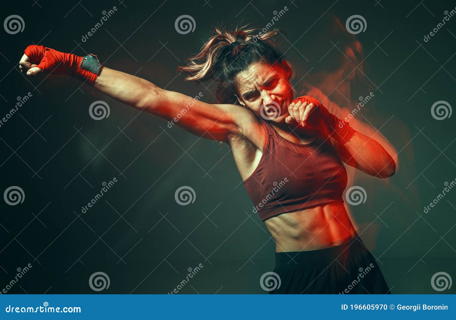 cool girl fighter with relief abs makes jab in studio in neon light. sport and motivation concept. long exposure shot