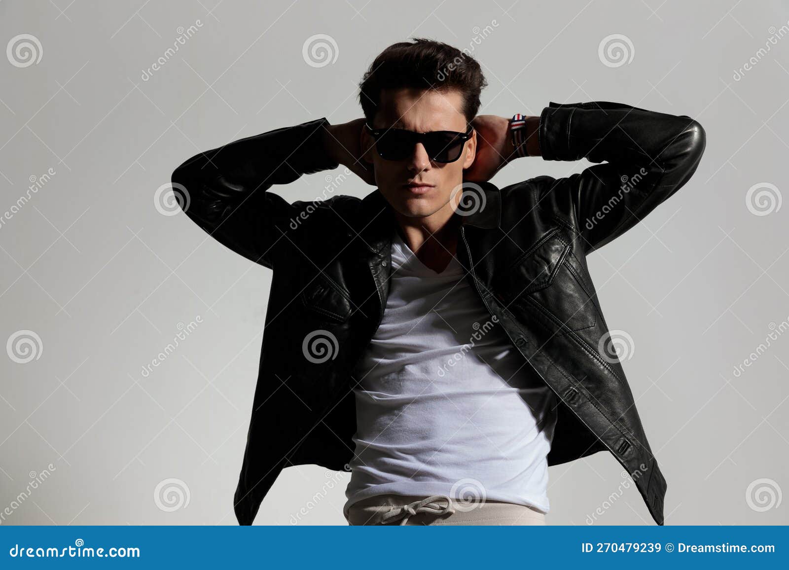 Cool Guy in Leather Jacket Holding Hands Behind Neck and Posing Stock