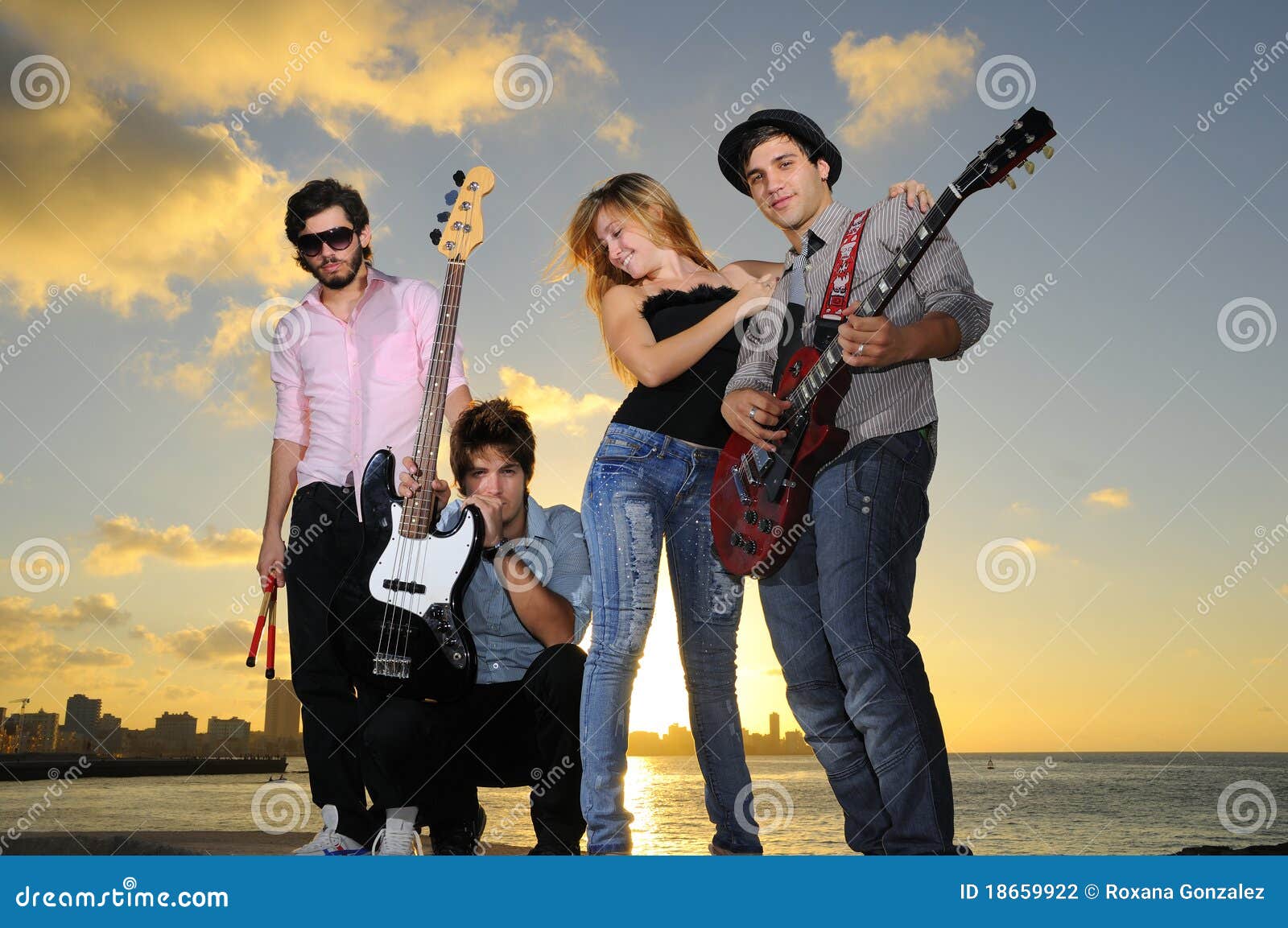 Cool young musical band posing at sunset. Portrait of young musical band posing outdoors at sunset with instruments