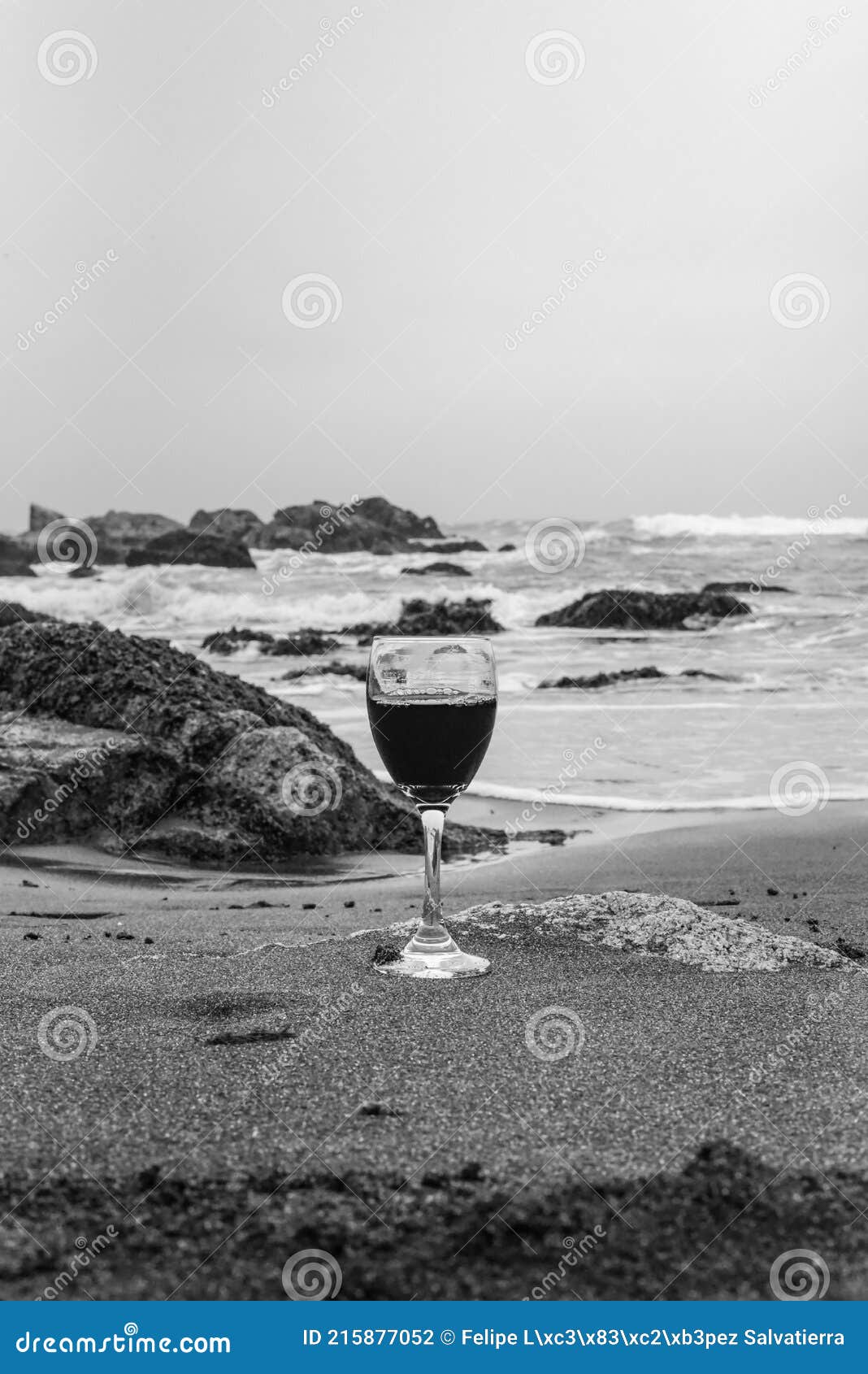 copa de vino tinto en la playa de arena blanco y negro