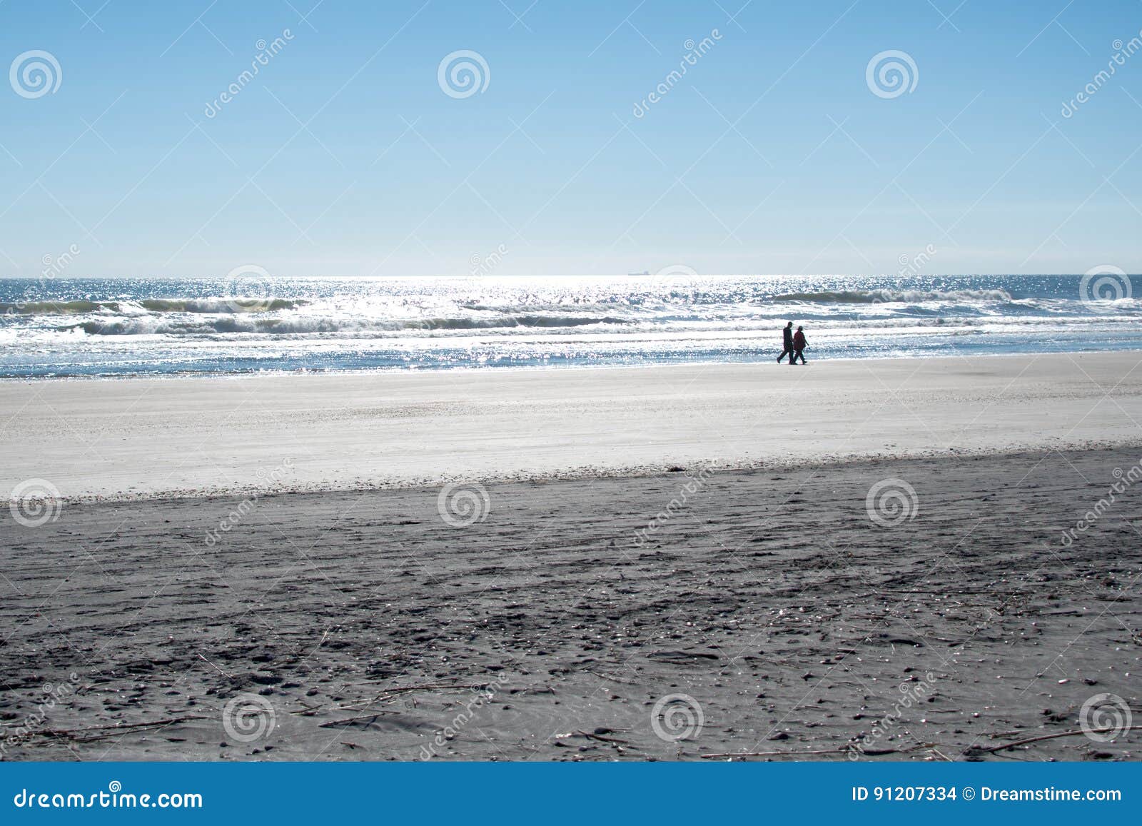 Coppia la camminata lungo il litorale su una spiaggia in Florida. Siluetta delle coppie che camminano lungo il litorale su una spiaggia in Florida con il sole che splende sull'acqua