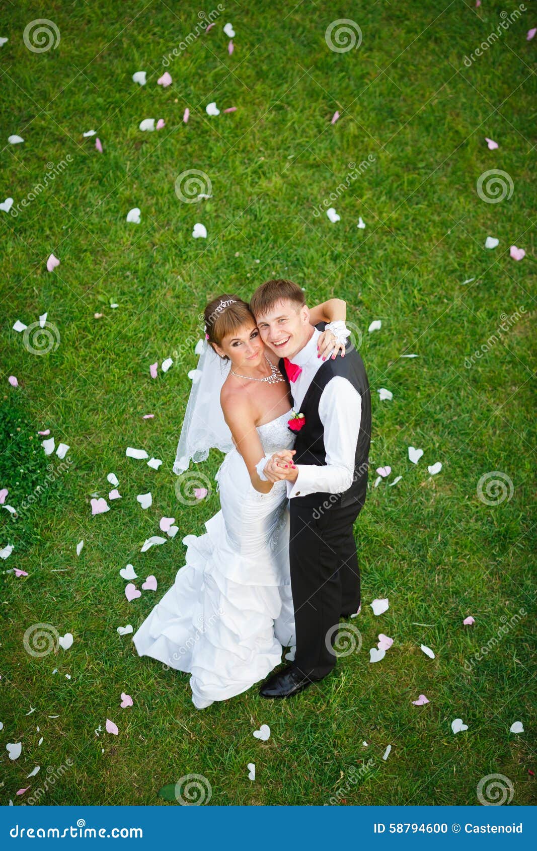 Coppie felici di nozze che stanno sull'erba verde all'ora legale