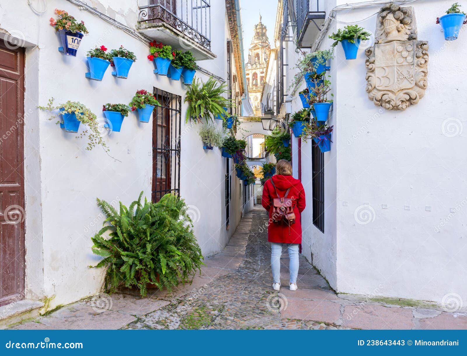 cordoba, spain. beautiful girl dressed in red looking at calleja de las flores, a famous narrow street in cordoba, spain during