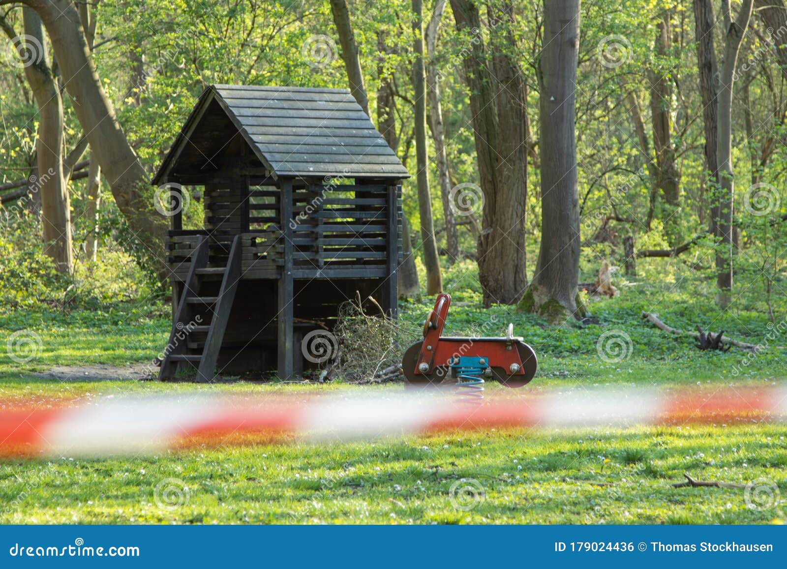 cordoned off playground, surroundet by trees, forcus on background, blurred barrier tape