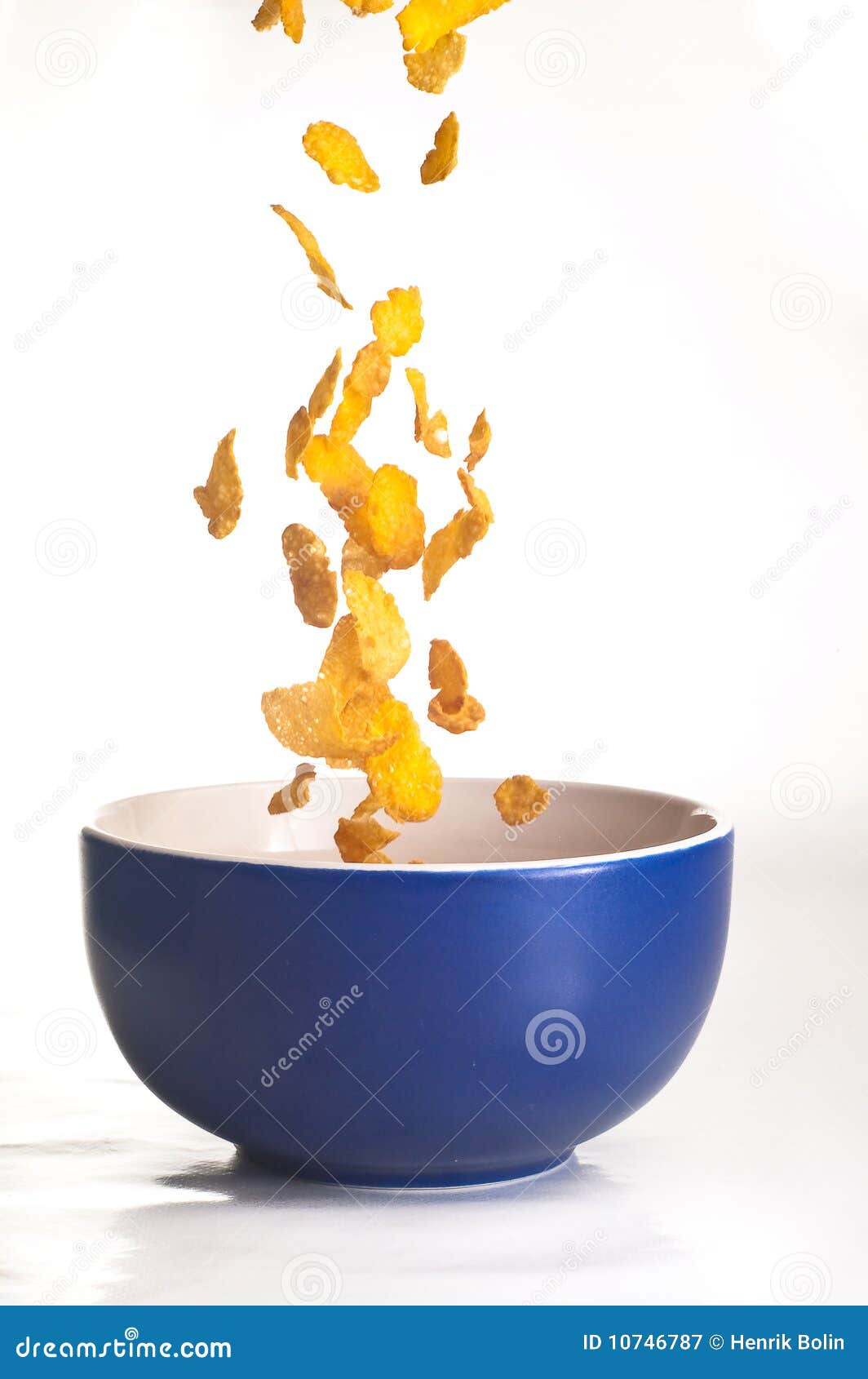 Cornflakes die op wit worden geïsoleerdo. De vlokken die van Conr in een kom vallen die op wit wordt geïsoleerde