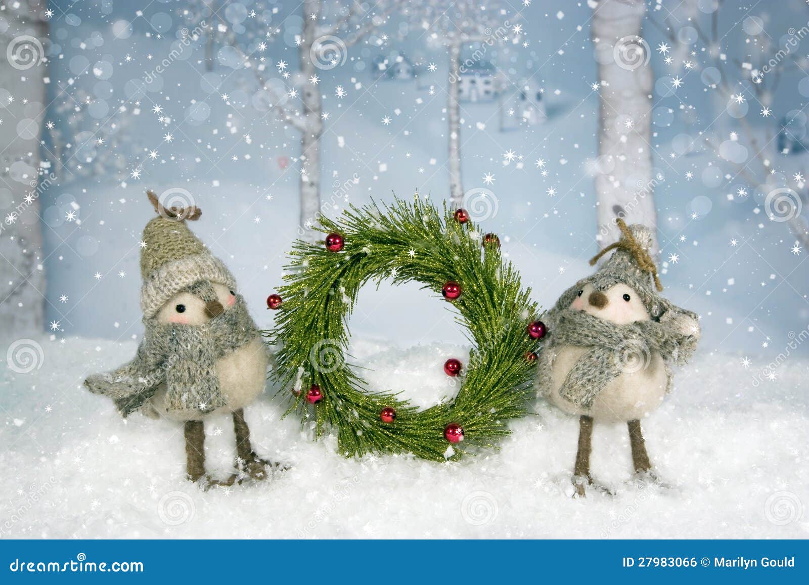 Corona degli uccelli di Natale. Una coppia gli uccelli capricciosi si è vestita in cappelli e le sciarpe che giudicano Natale si avvolgono. alberi e villaggio di betulla nel fondo.