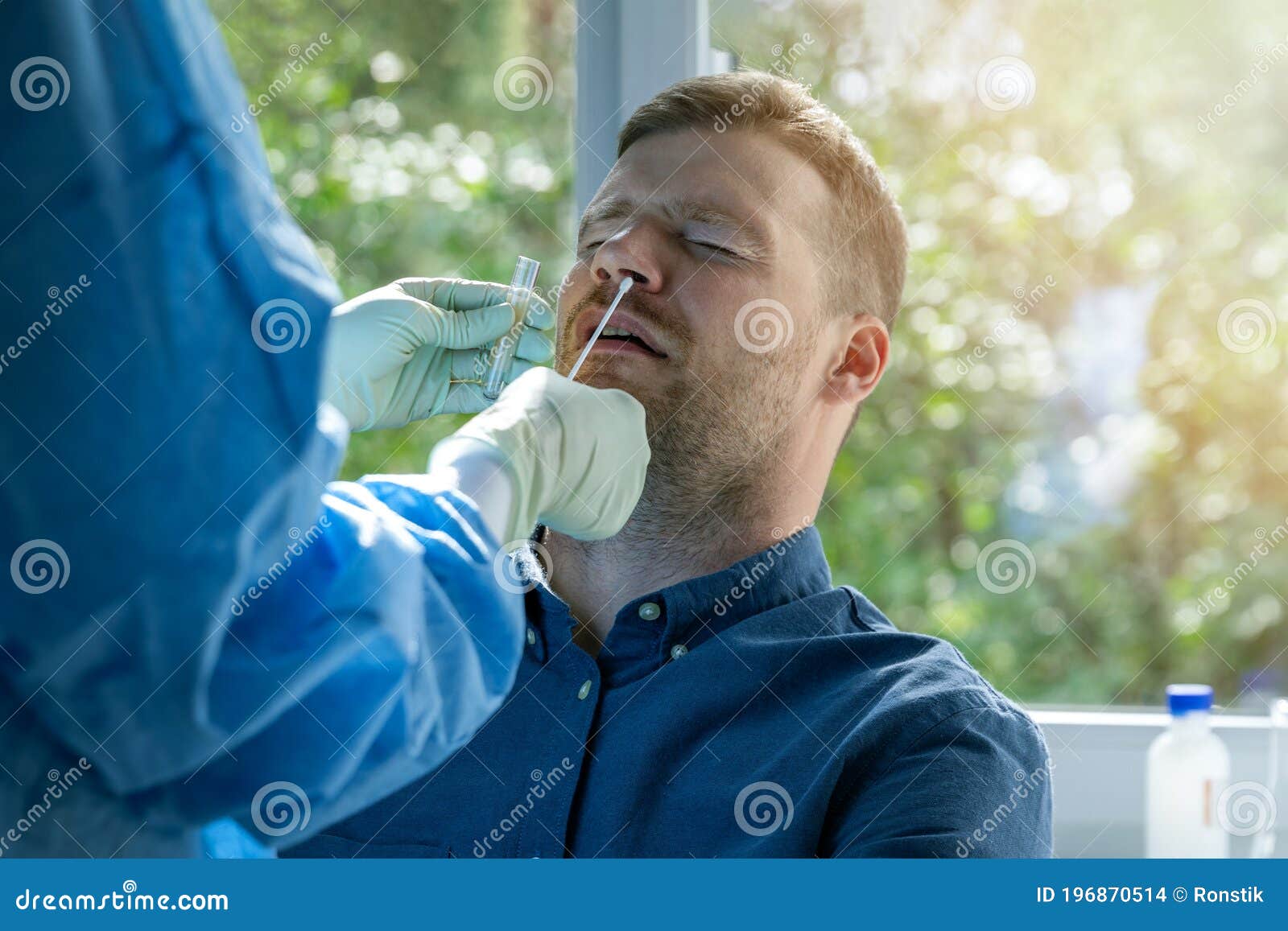 coronavirus nasal swab test -  lab worker taking a mucus sample from male patient nose