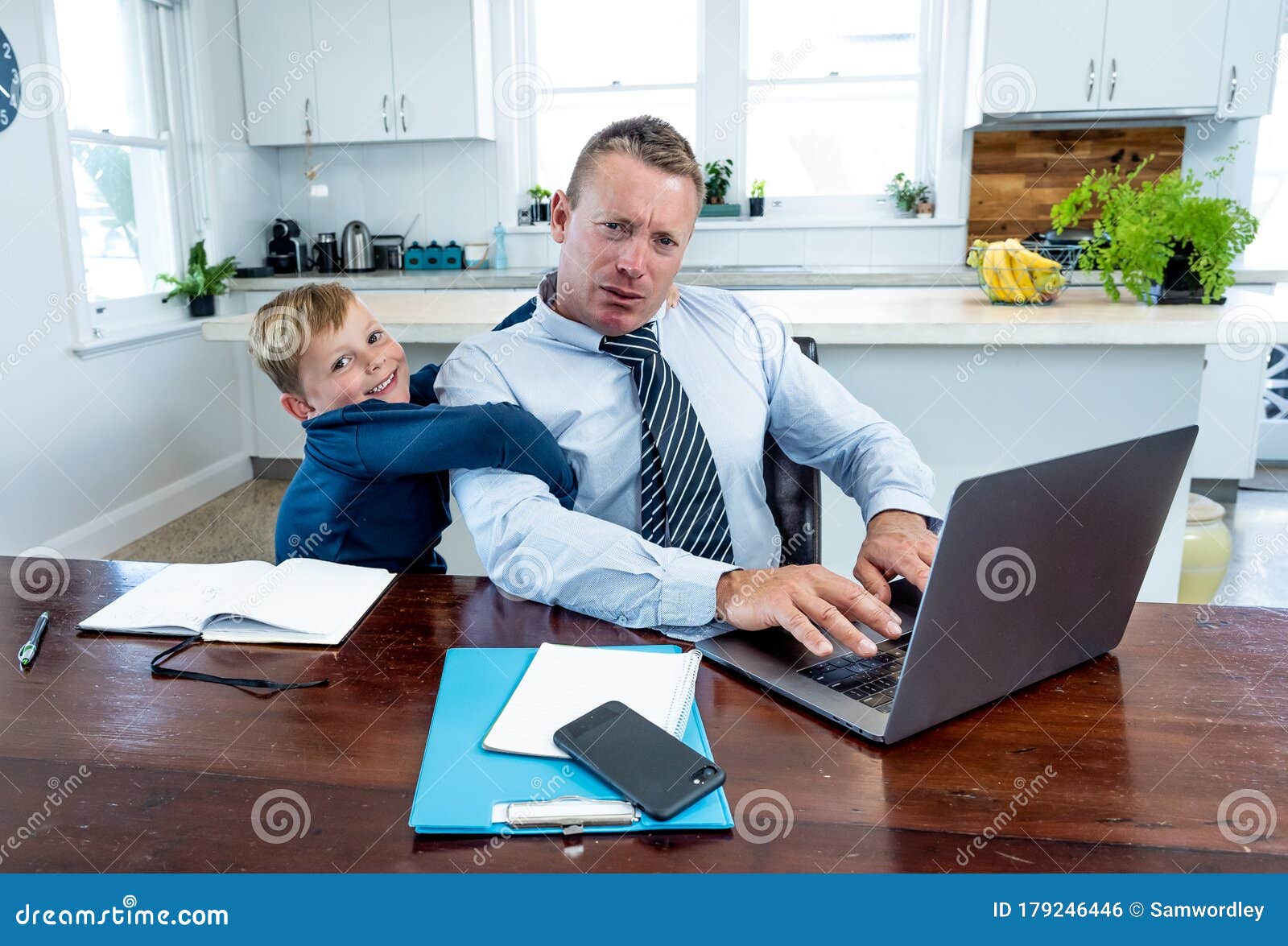 covid-19 school lockdowns and remote working. stressed man trying to work from home with bored son