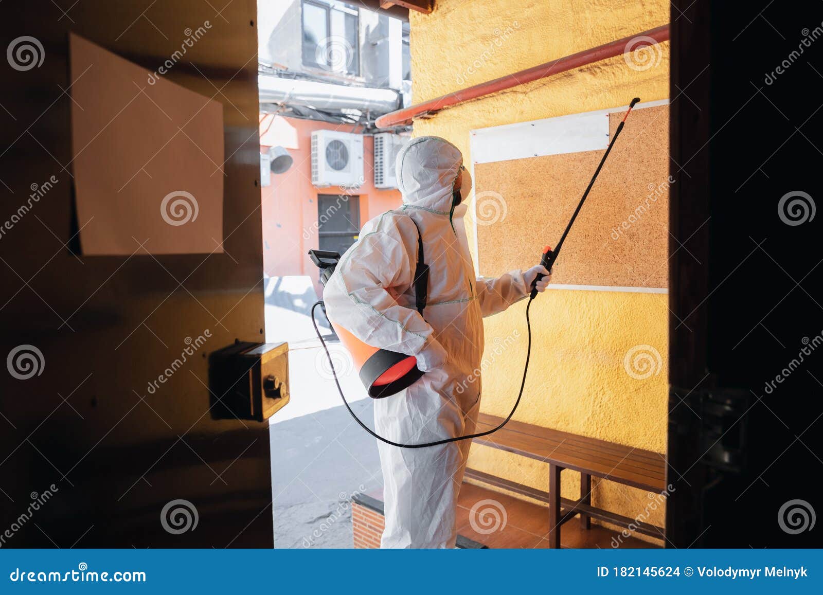 coronavirus pandemic. a disinfector in a protective suit and mask sprays disinfectants in the house or office