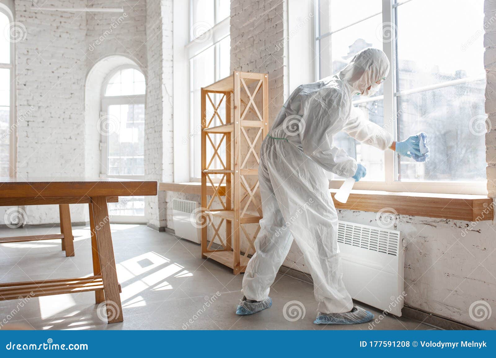 coronavirus pandemic. a disinfector in a protective suit and mask sprays disinfectants in the house or office