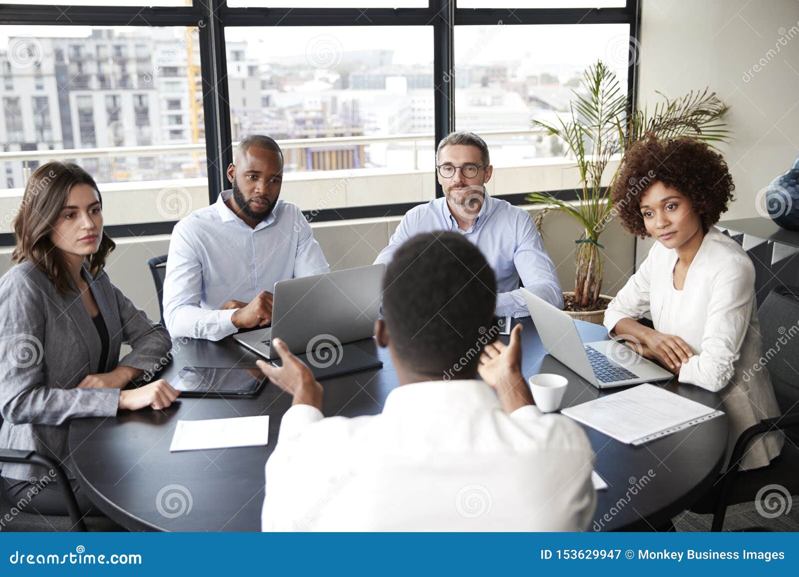 corporate business people in a meeting room listening to a colleague speaking, elevated view