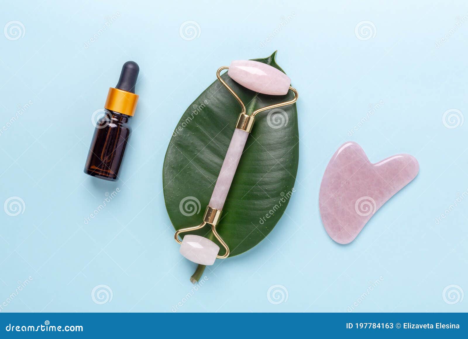 cosmetic bottles, face serum, facial massage roller and gua sha massager on blue background. anti age, lifting and toning