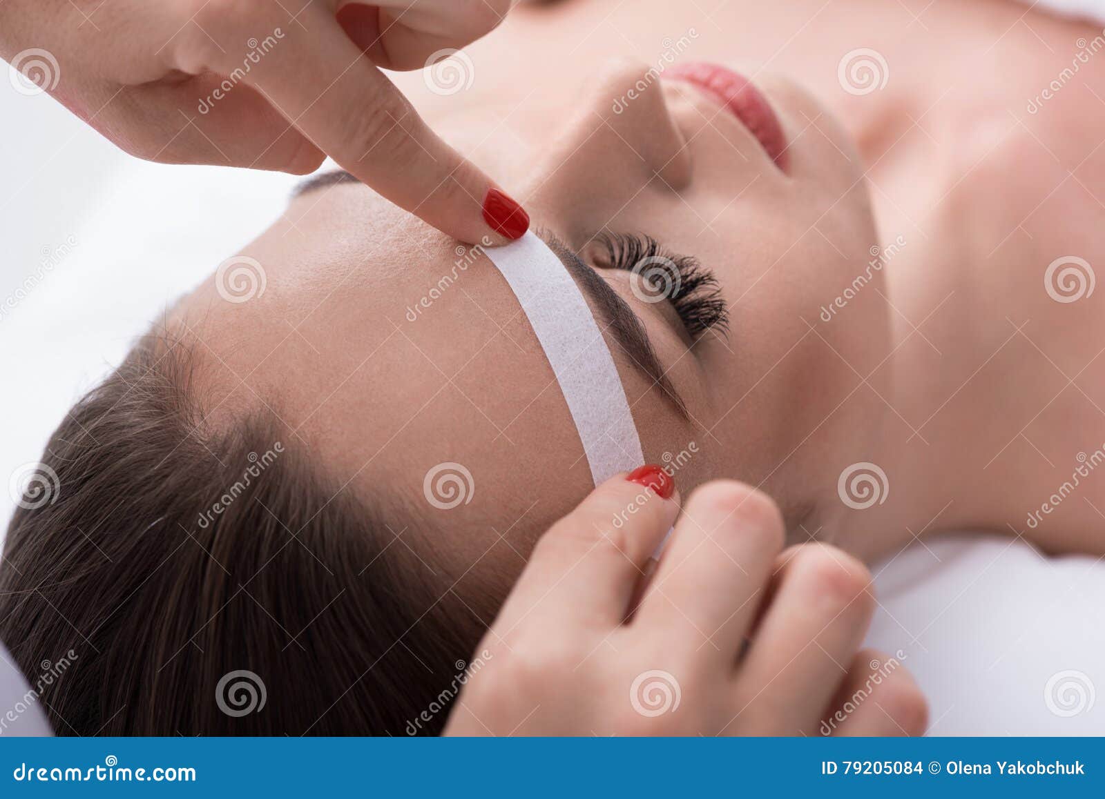 cosmetician undergoing waxing procedure for human brow