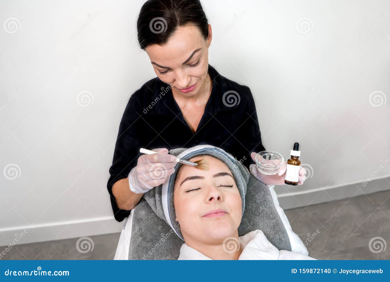 Cosmetologist Administering Chemical Peel Treatment On Patient In A