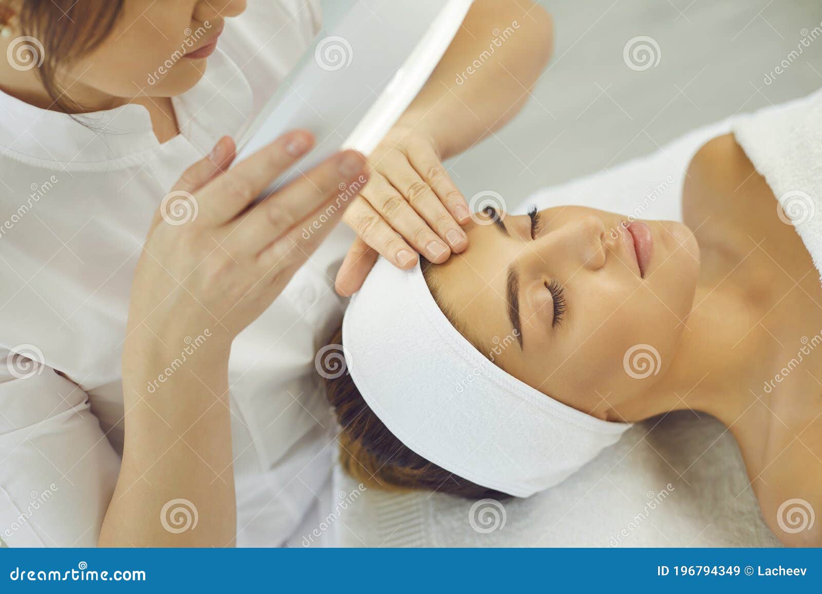 cosmetologist checking skin elasticity and making examination for young relaxing woman