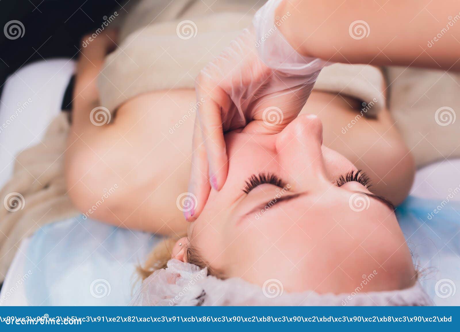 cosmetologist makes a buccal massage of the patient`s facial muscles.